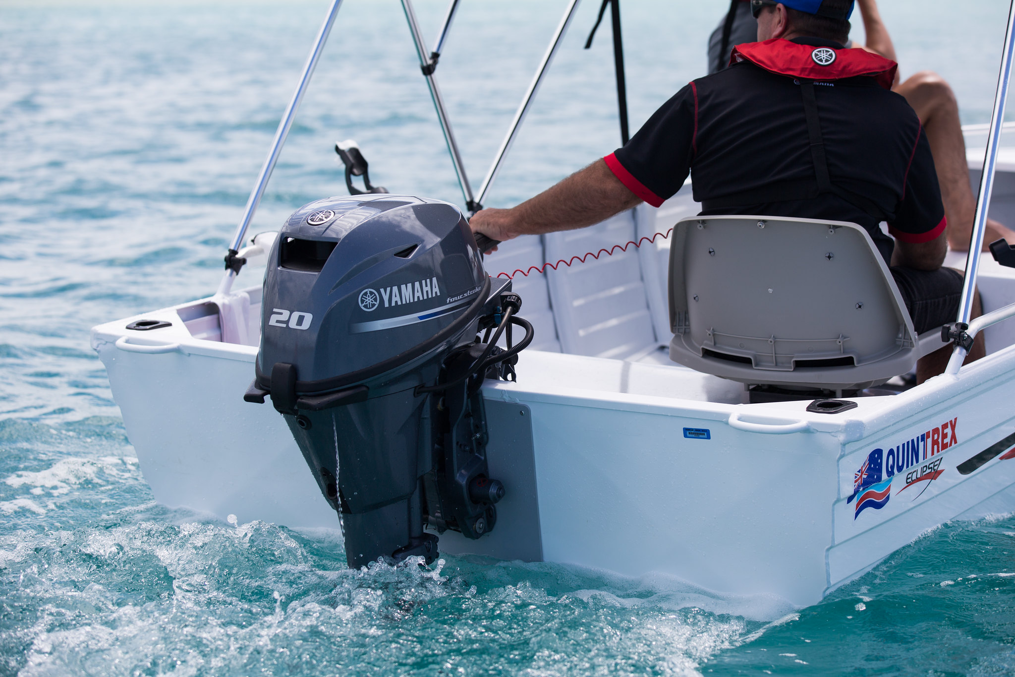 A man operating an outboard motor attached to the Quintrex boat.