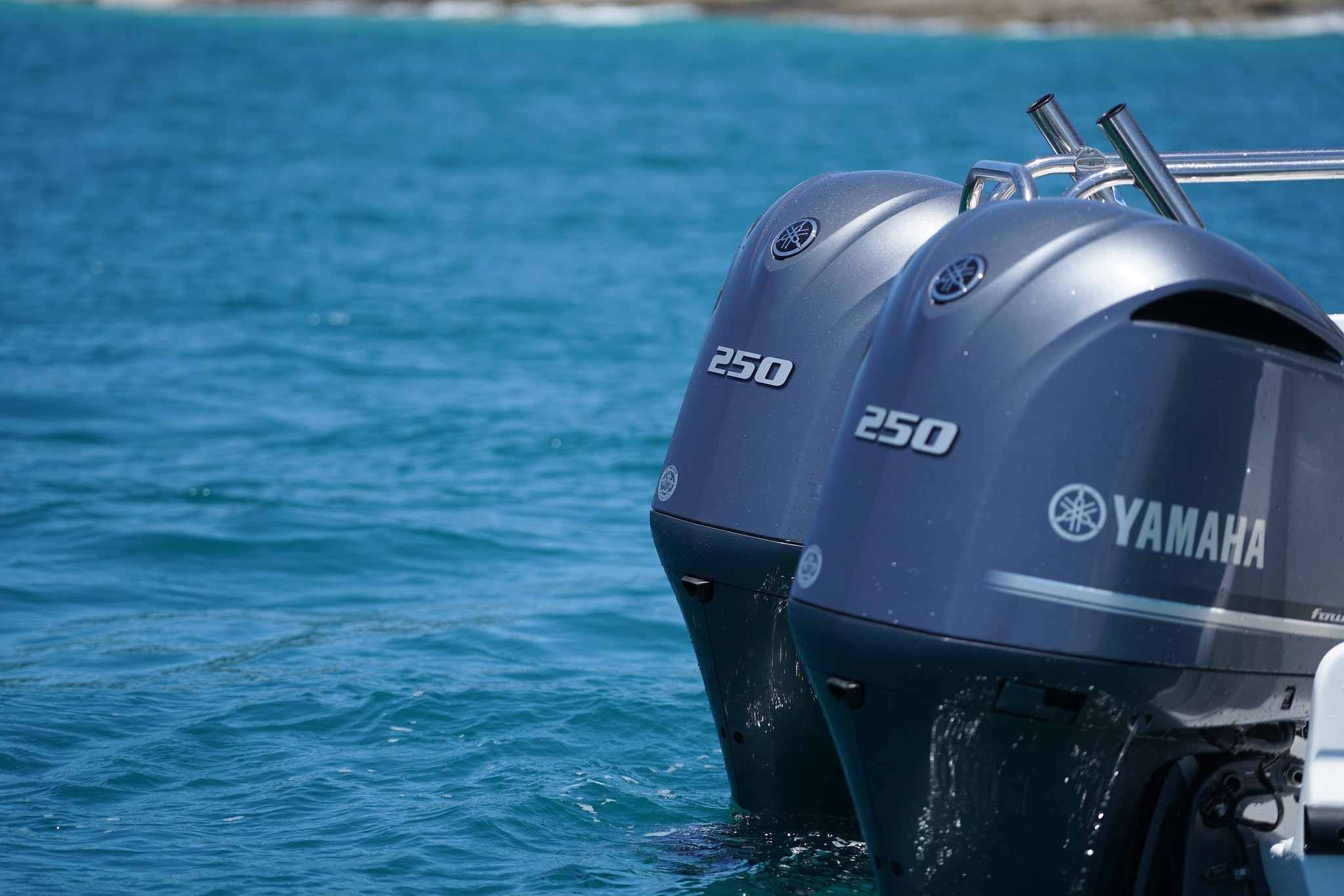 A close up shot of Yamaha outboard engines on idle at a body of water.