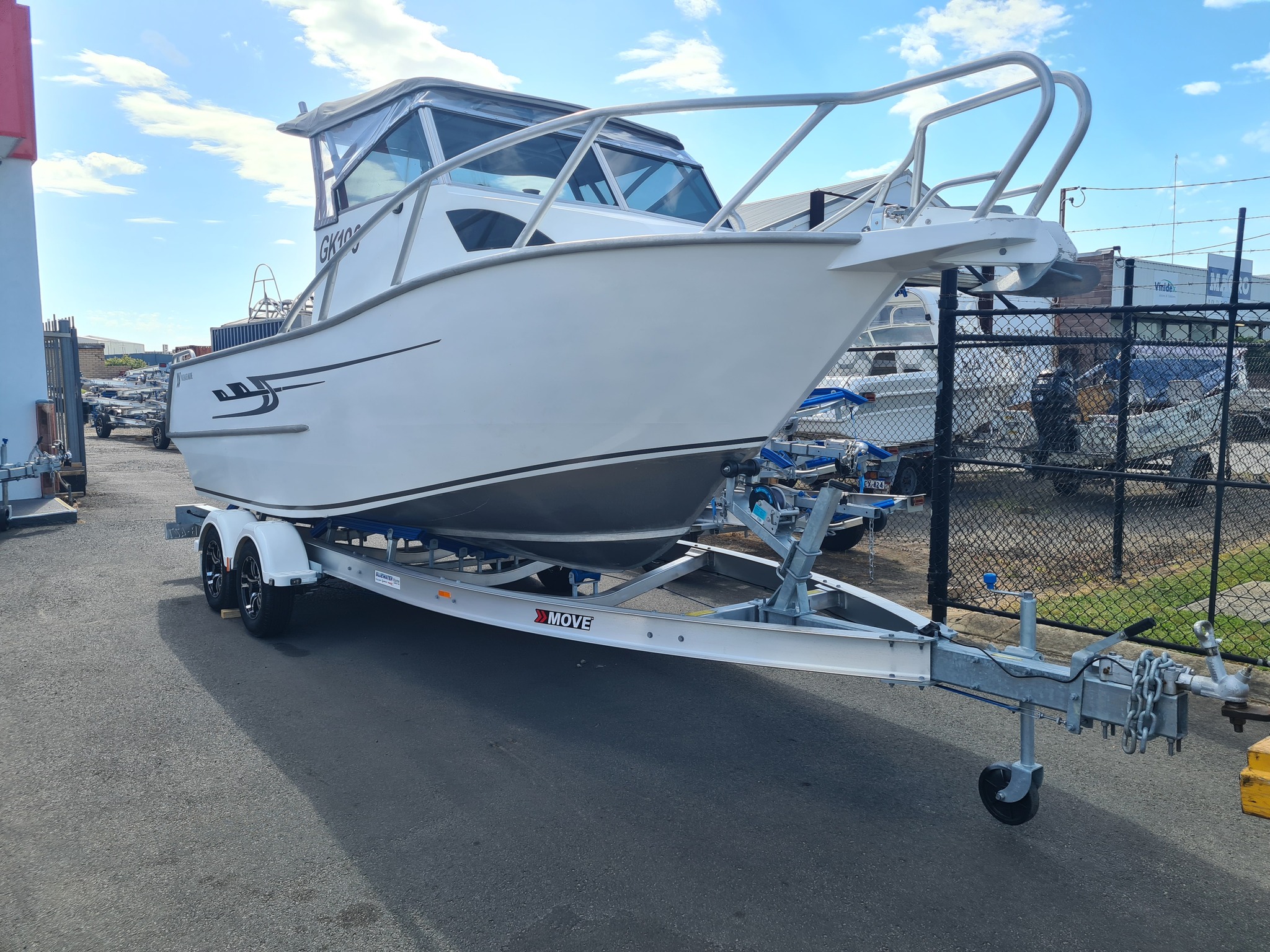 A boat on a trailer parked in a dealership's yard.