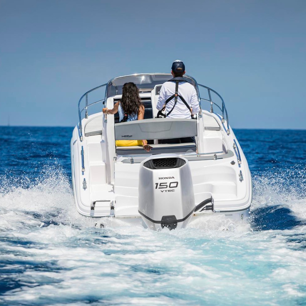 Two people onboard a white boat while it's underway.