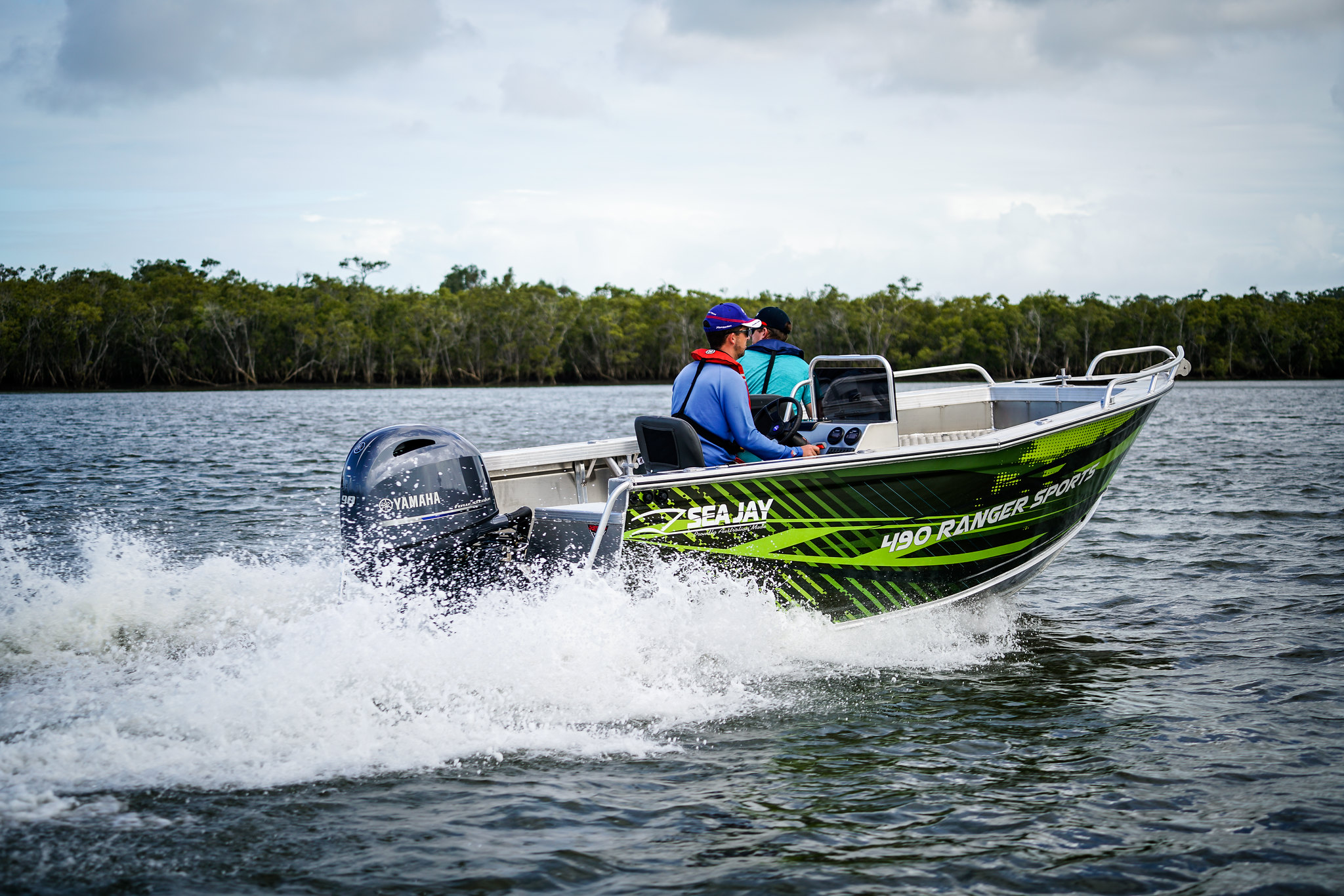 A green open boat operated by a man on a lake