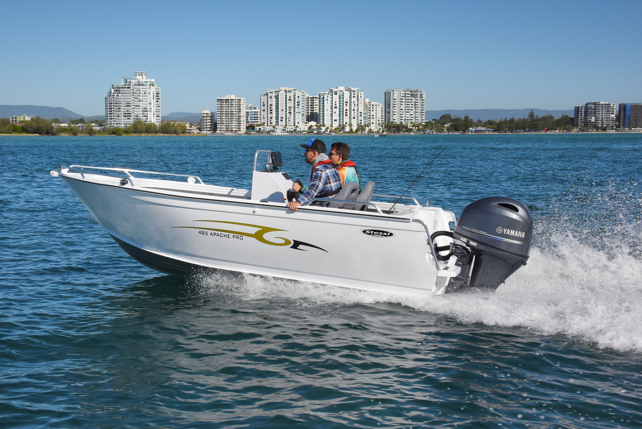 Two men operating a white boat at a lake.