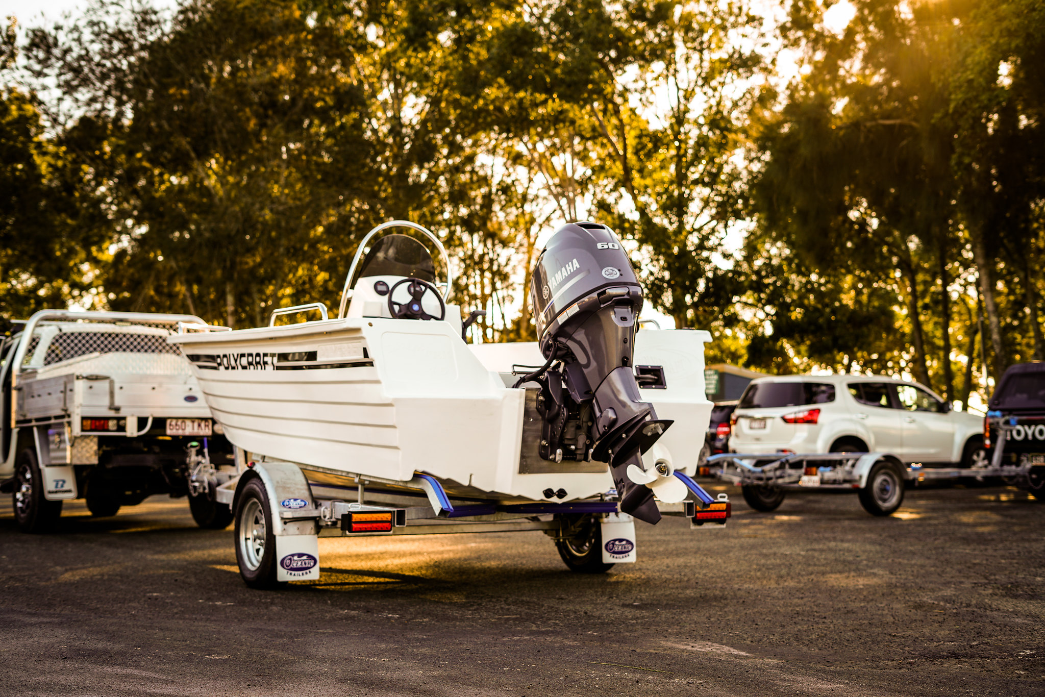 A Polycraft boat perched on top of a boat trailer is parked on a driveway.