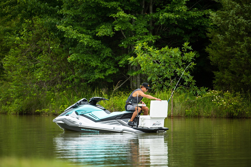 A man on jetski opening a cooler perched on top of the jet ski