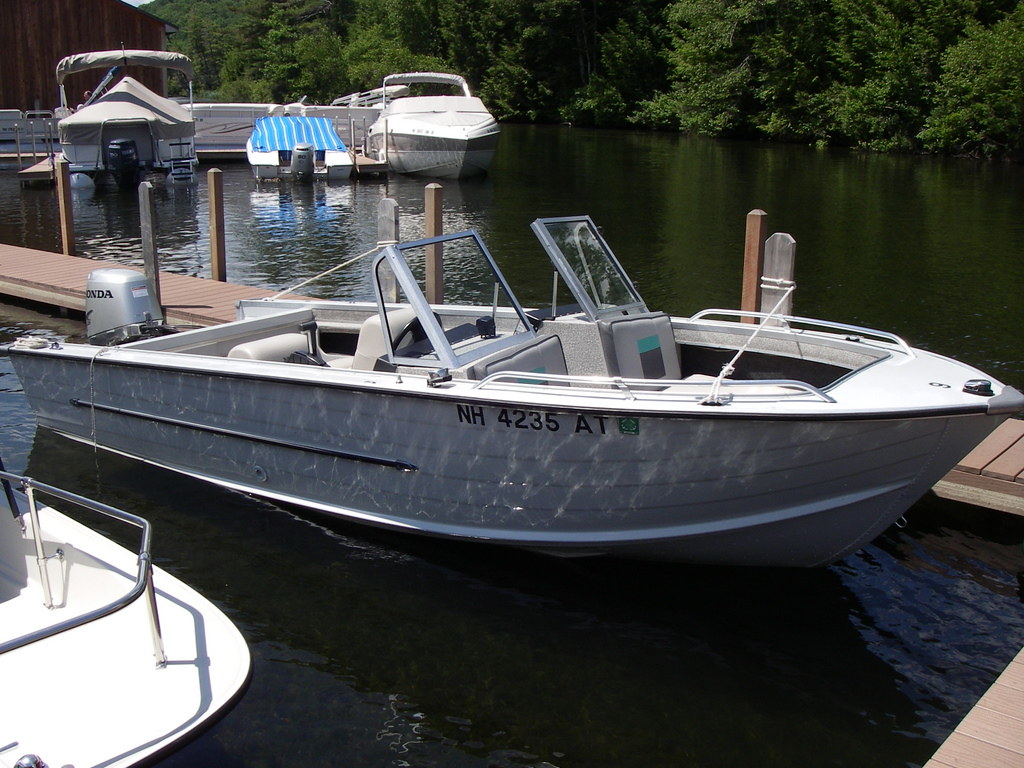 A wide shot of an aluminium boat moored next to a dock.