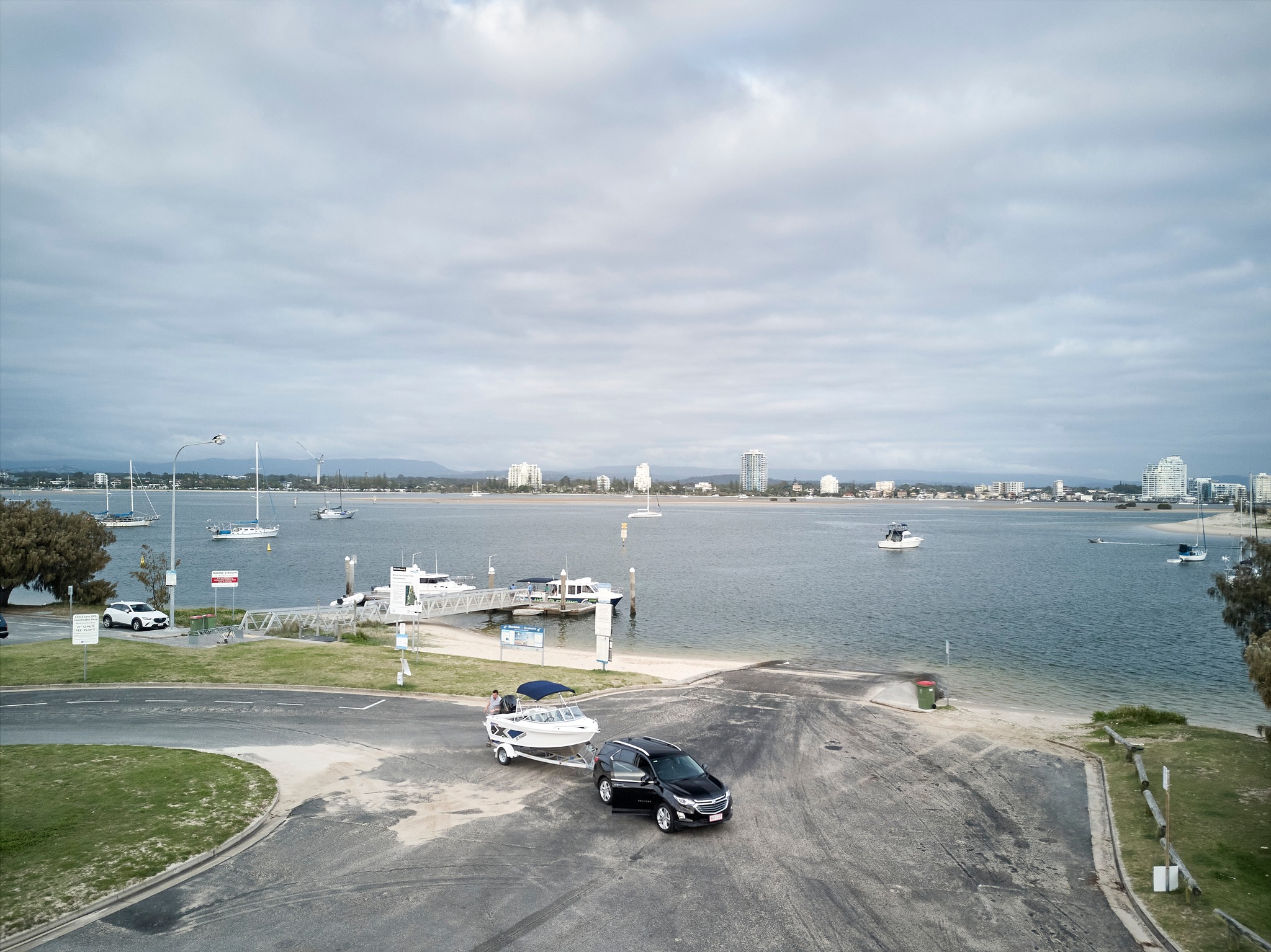 a vehicle towing a boat and a trailer near a boat ramp.