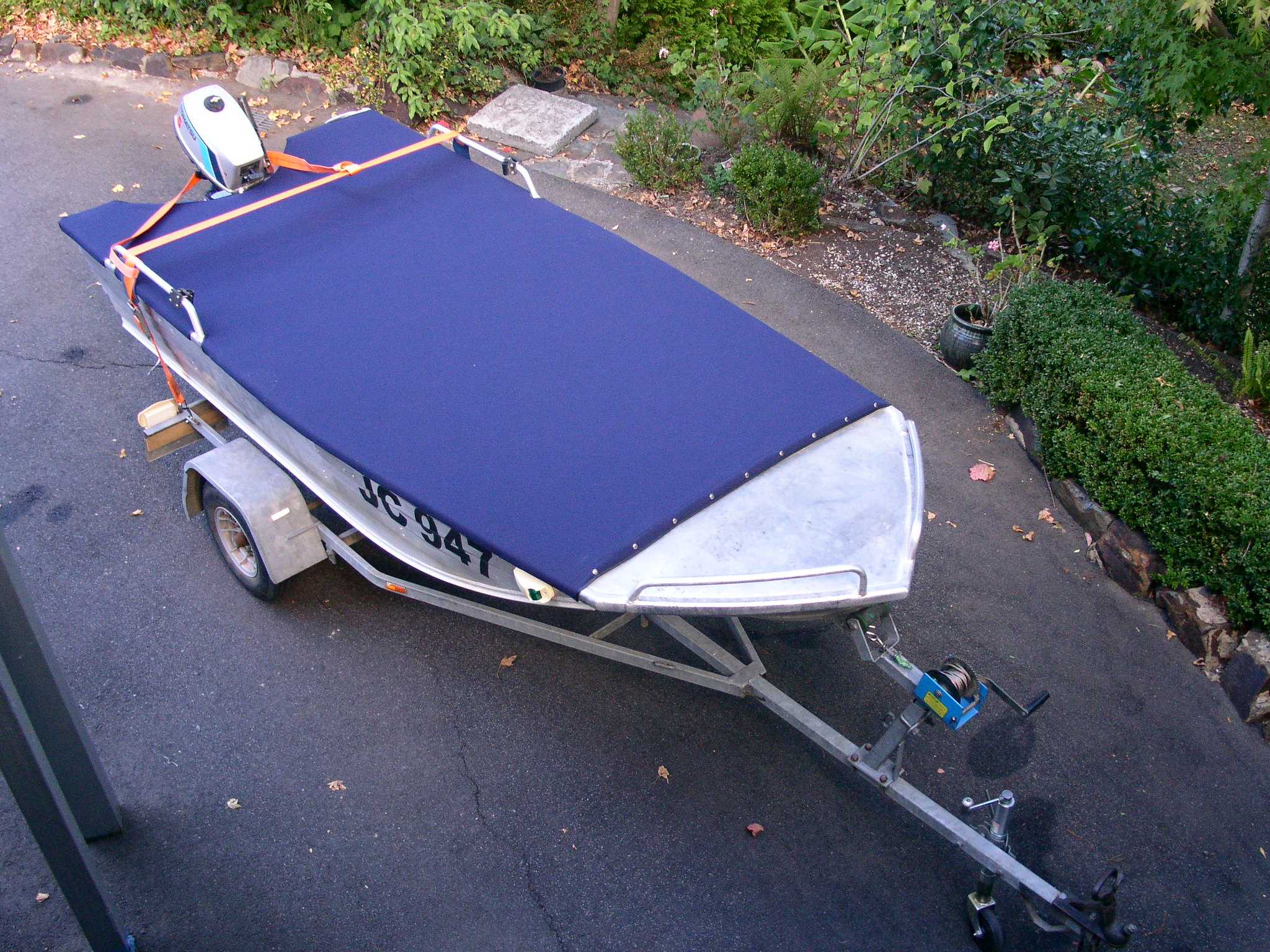 A boat with a cover on a boat trailer.