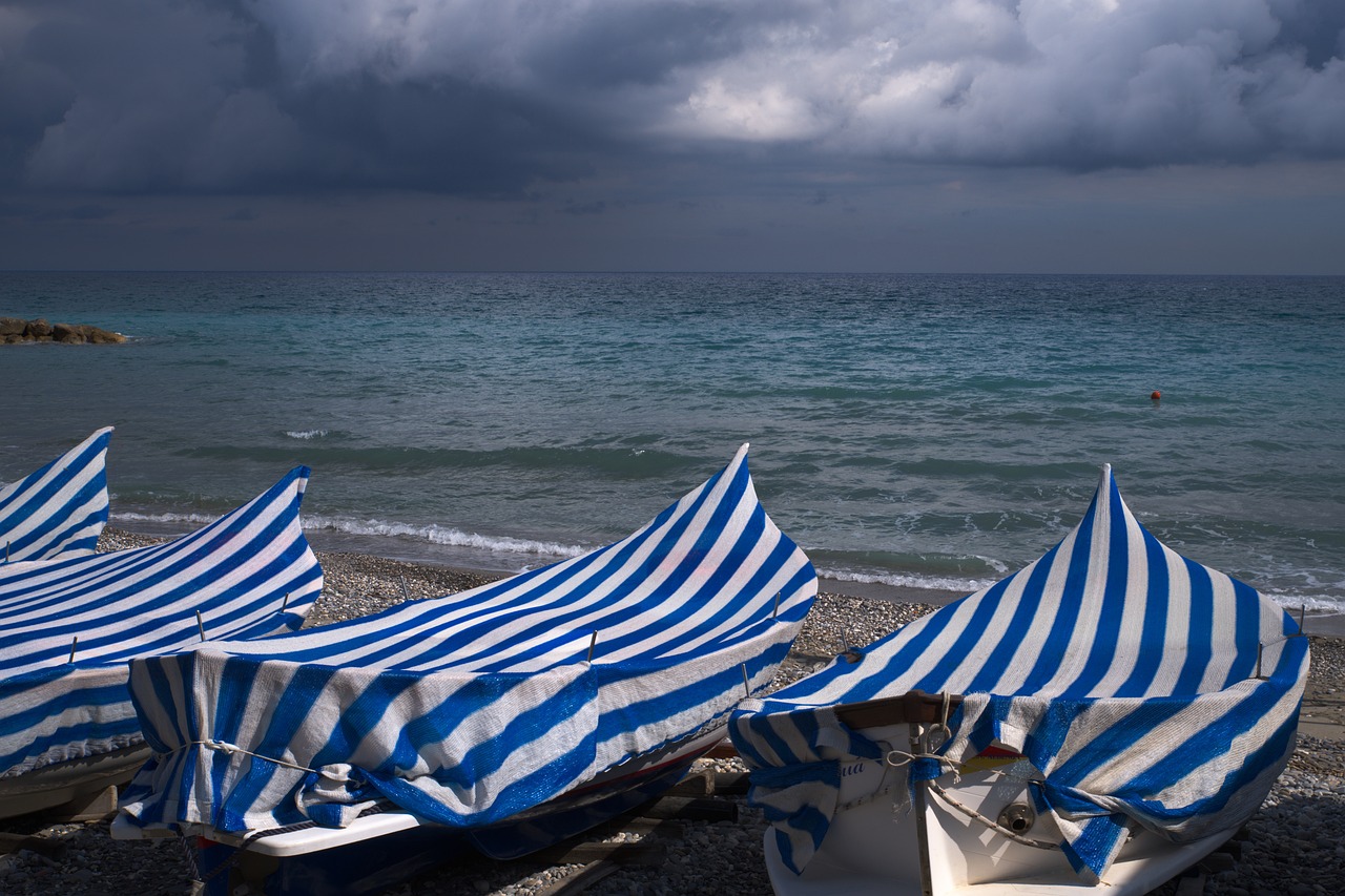 boats with blue and white stripes boat cover docked at the beach.