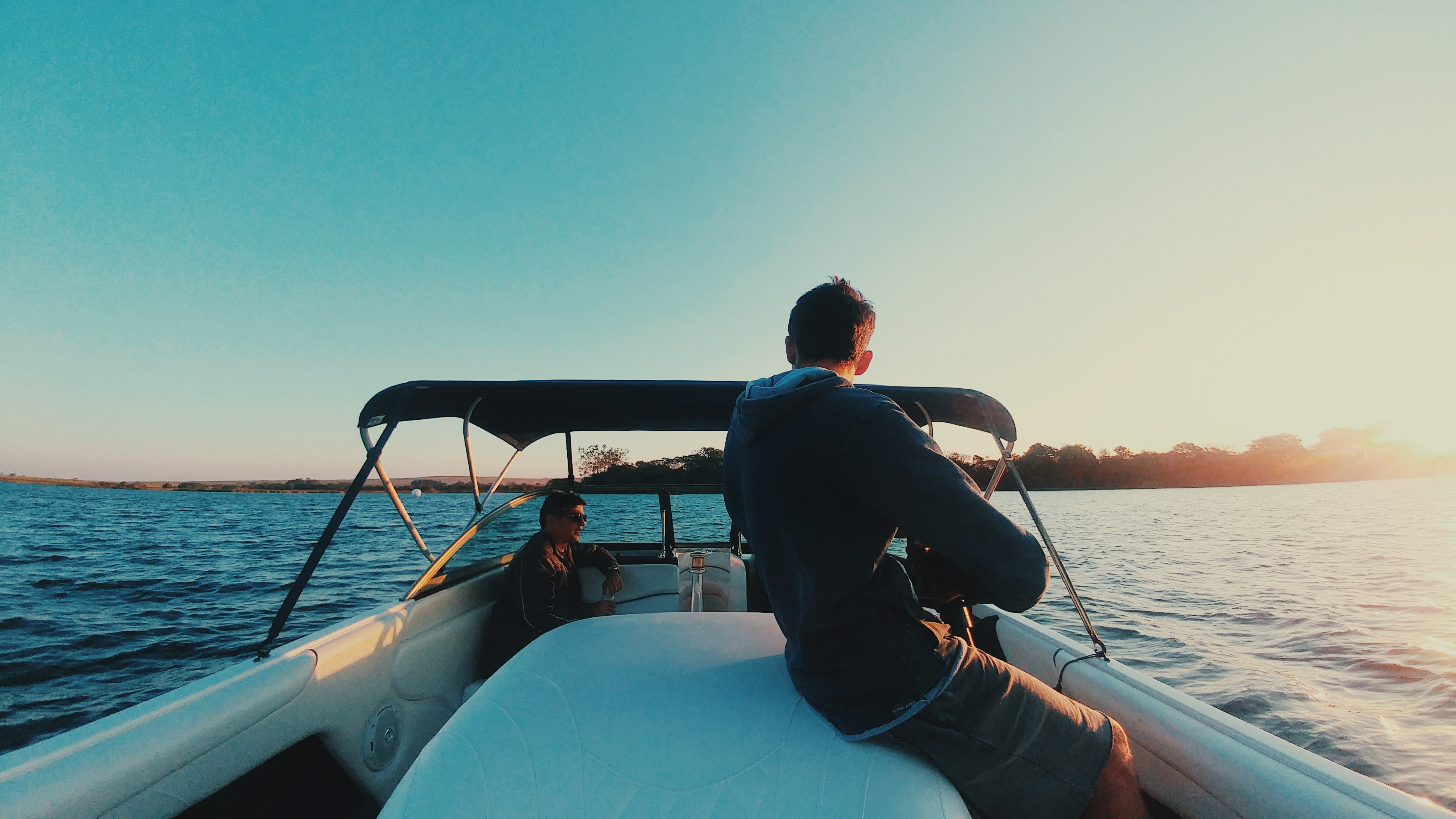 Two people onboard a boat with a Bimini top.