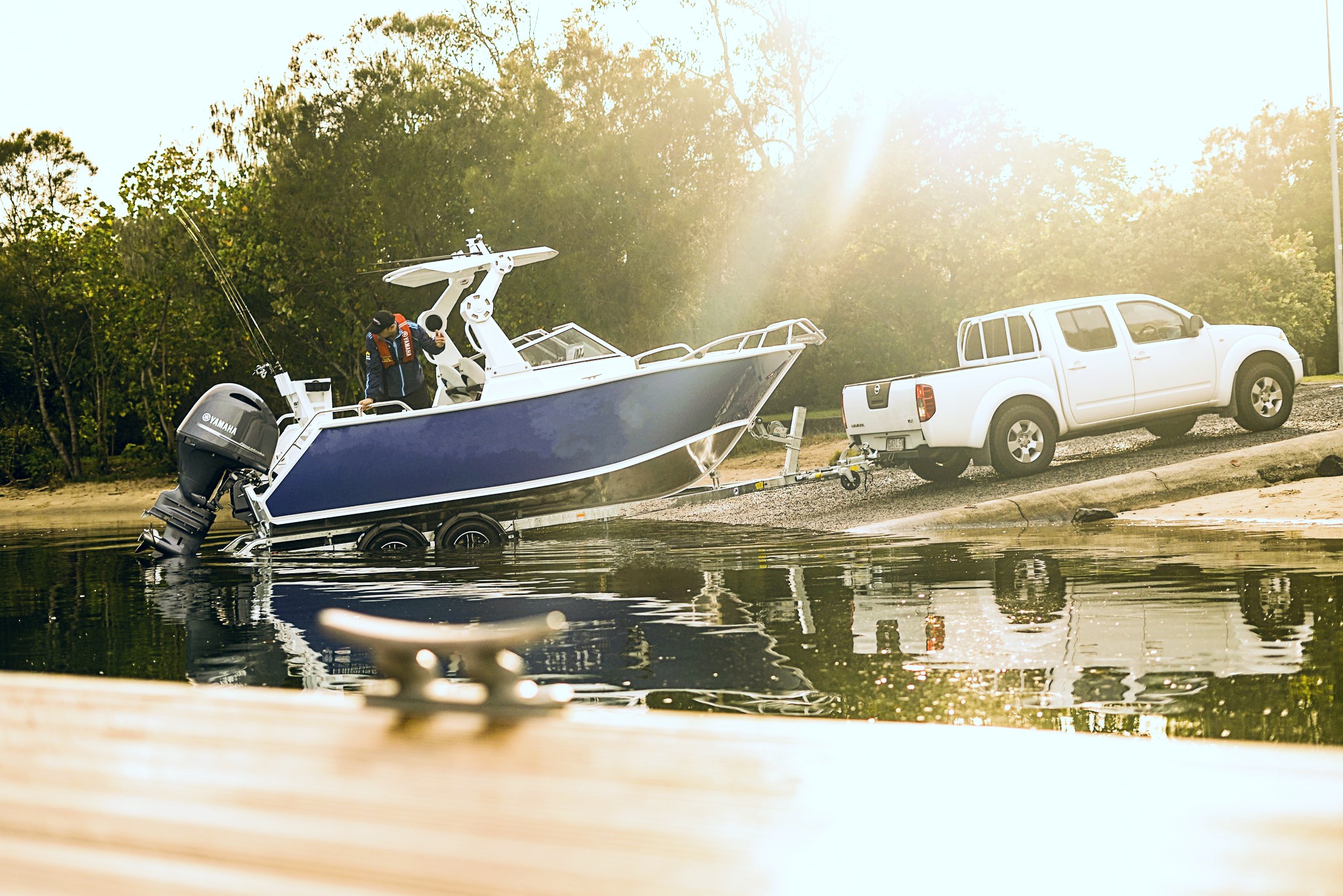 A vehicle pulling a boat and a trail out of the water.