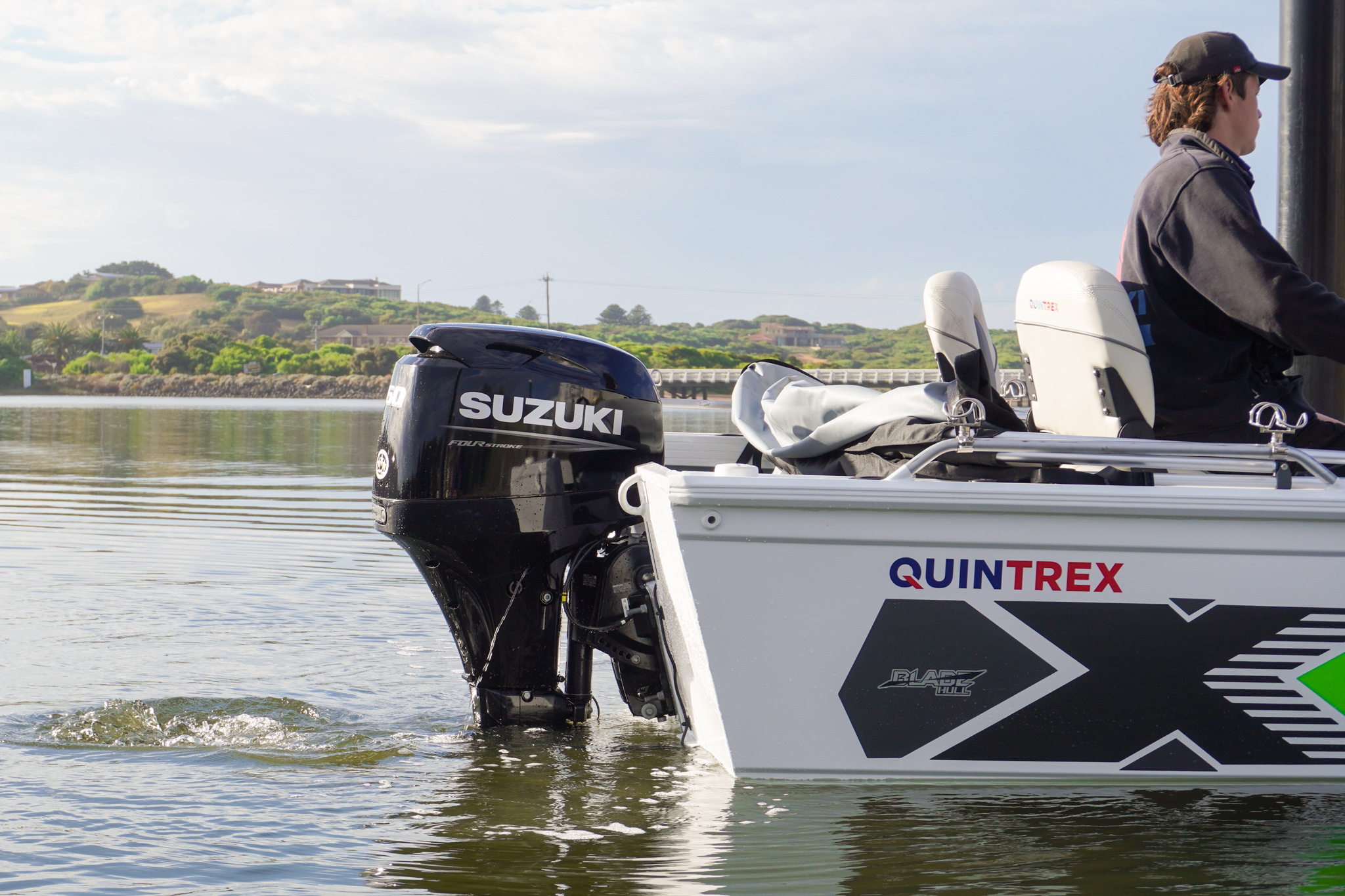 A Quintrex boat equipped with a Suzuki outboard is being operated by a man.