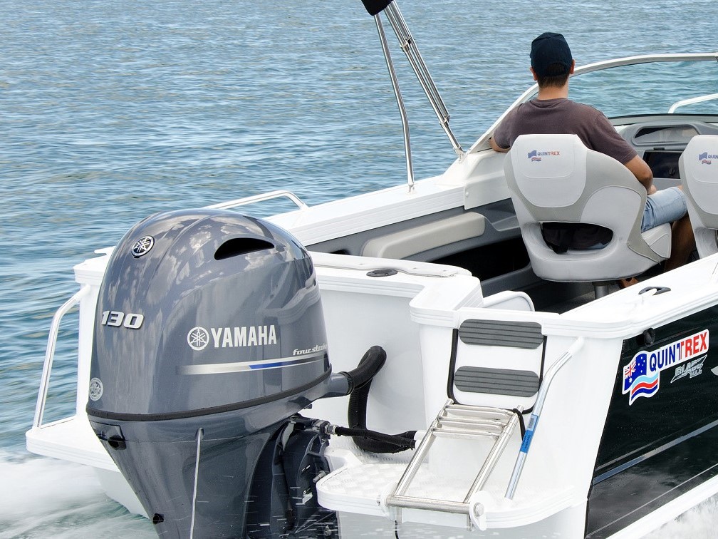 A view of a Quintrex boat's transom with an outboard motor attached on it while two men are operating the boat.