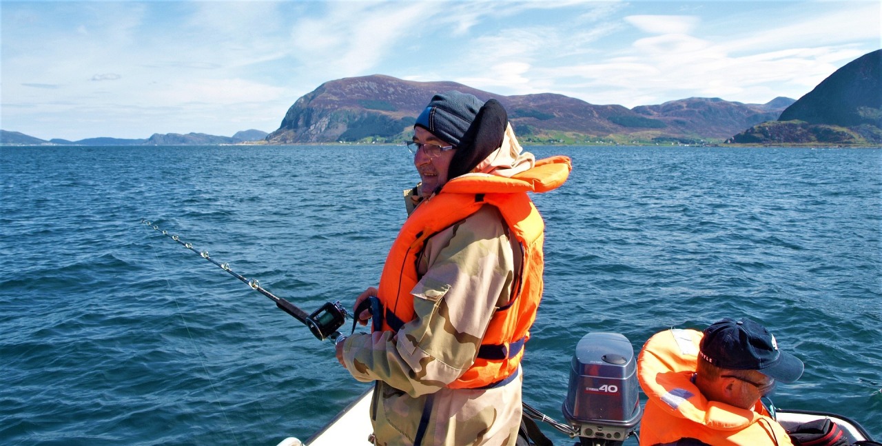 Men wearing a life jacket while fishing at sea.