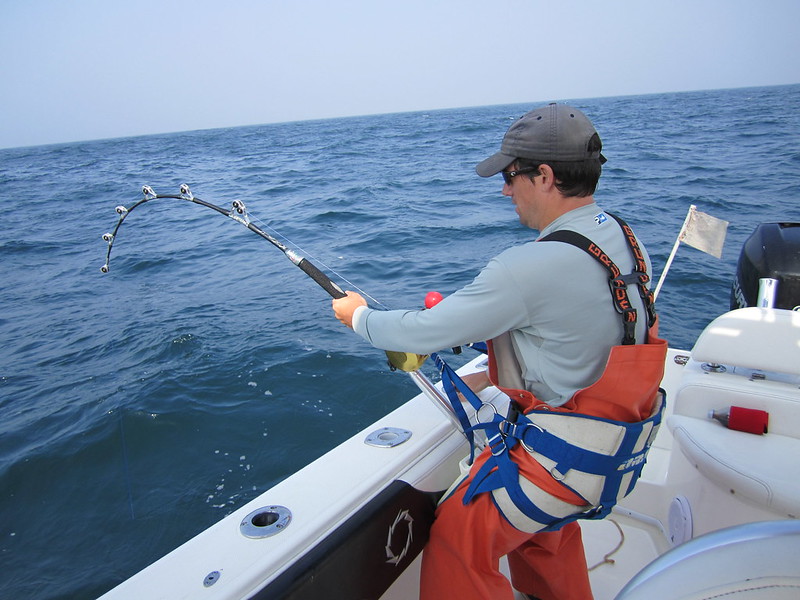 Man struggling to reel in a fish to the boat.