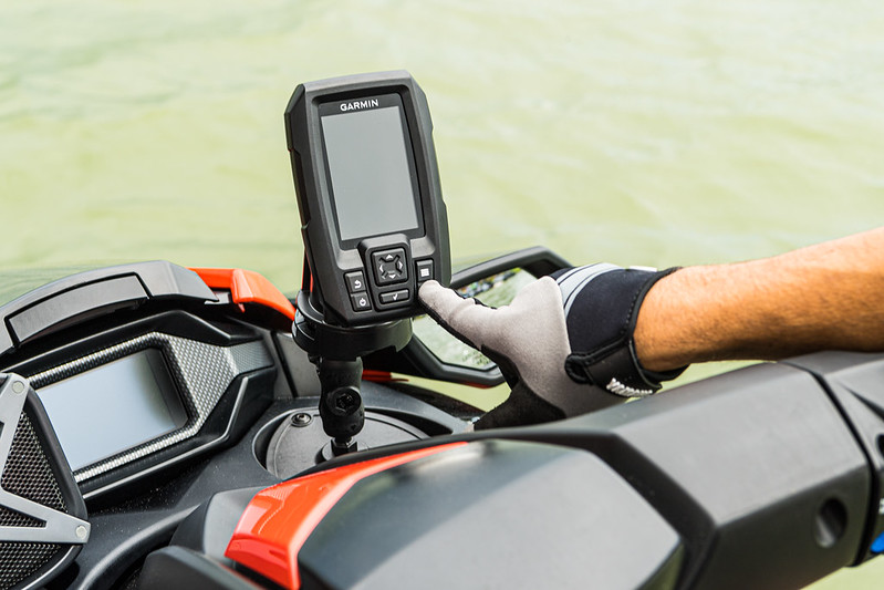 A hand pressing on a fishfinder's button.