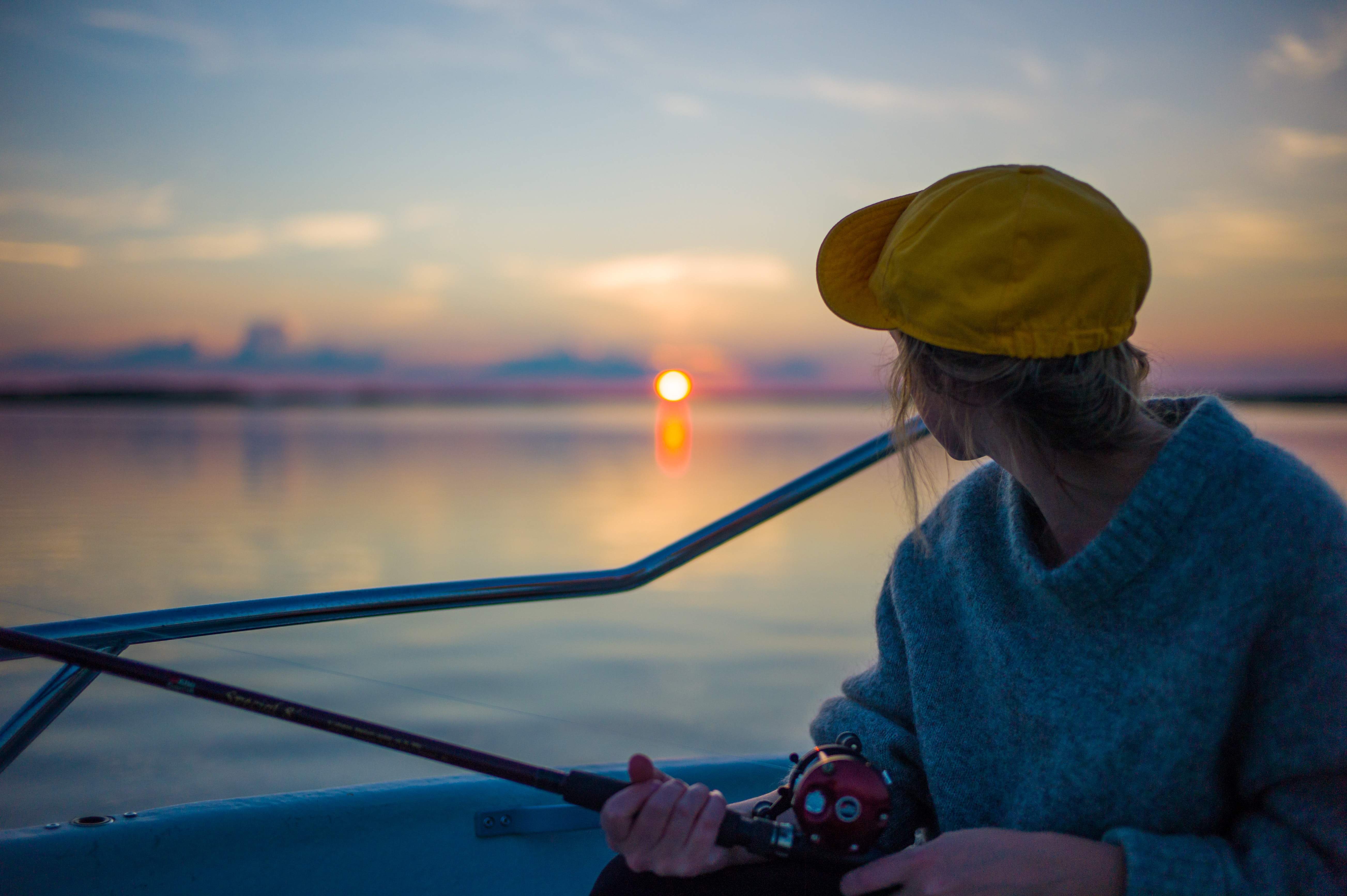 A girl staring to the ocean while fishing.