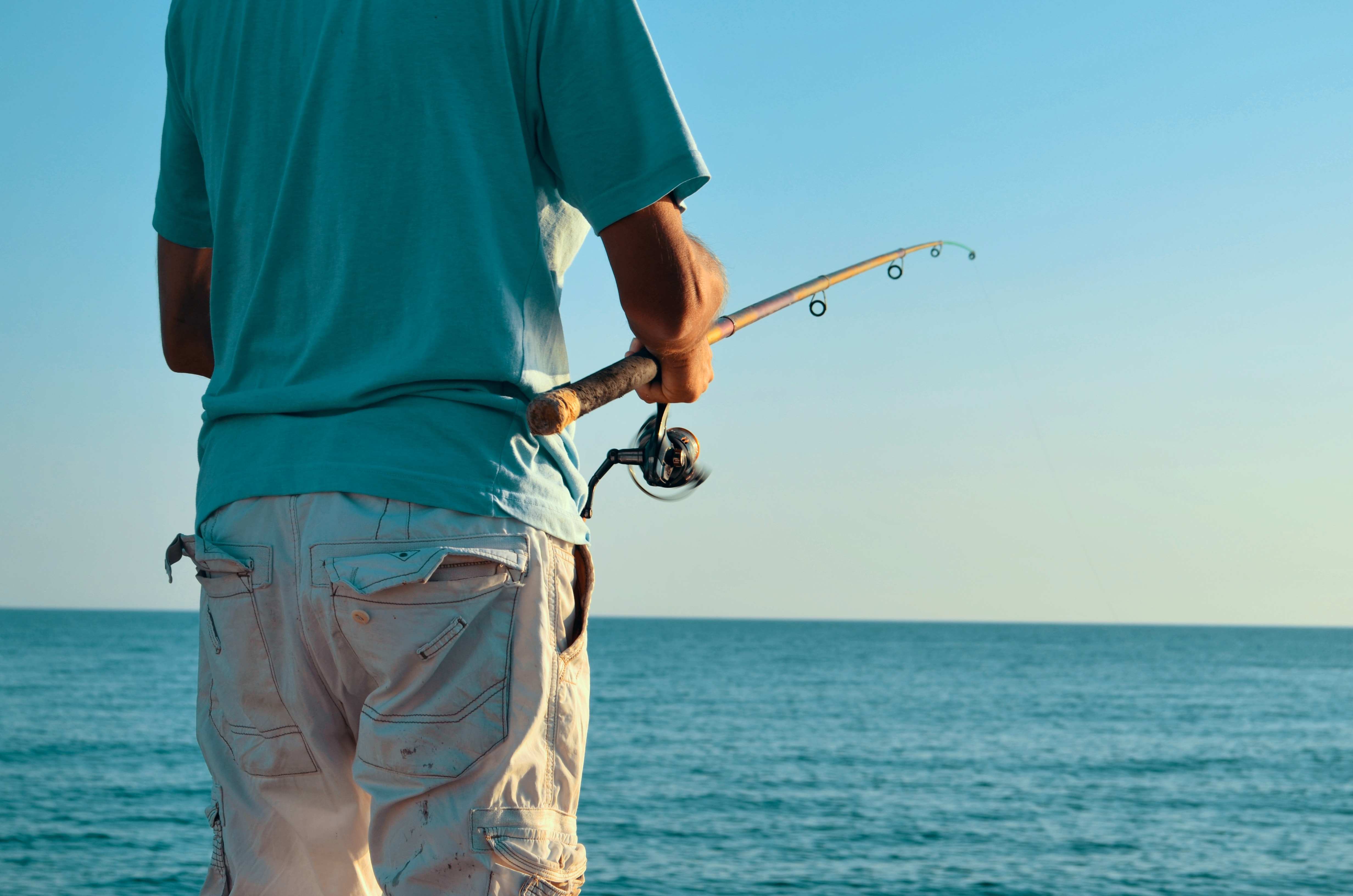 A man holding a fishing rod while fishing on a vast body of water