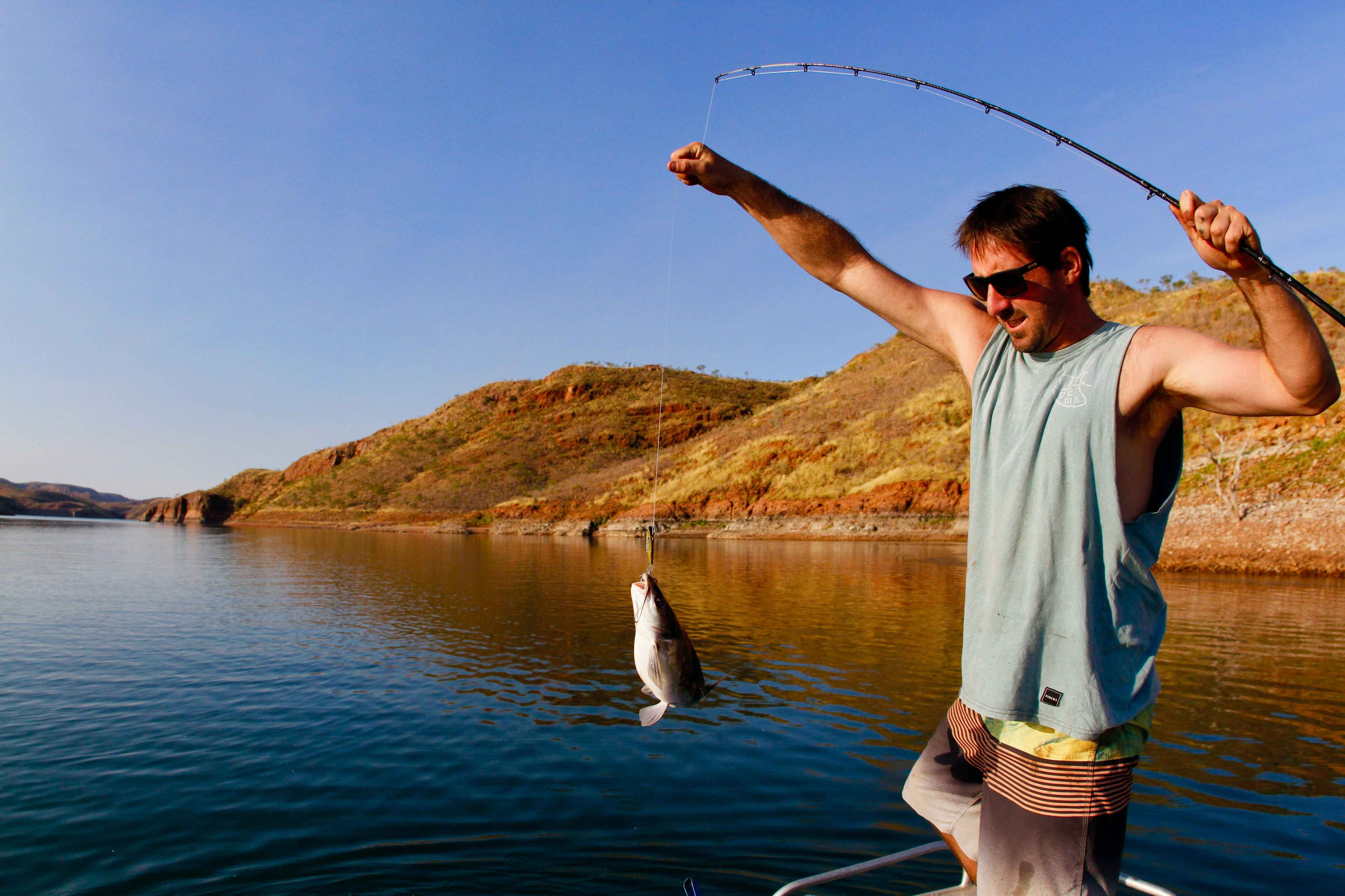 Man catching a fish with a fishing rod and a lure.