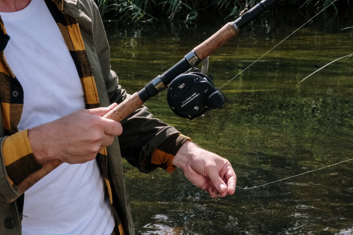 A man adjusting a fishing line from the fishing rod.