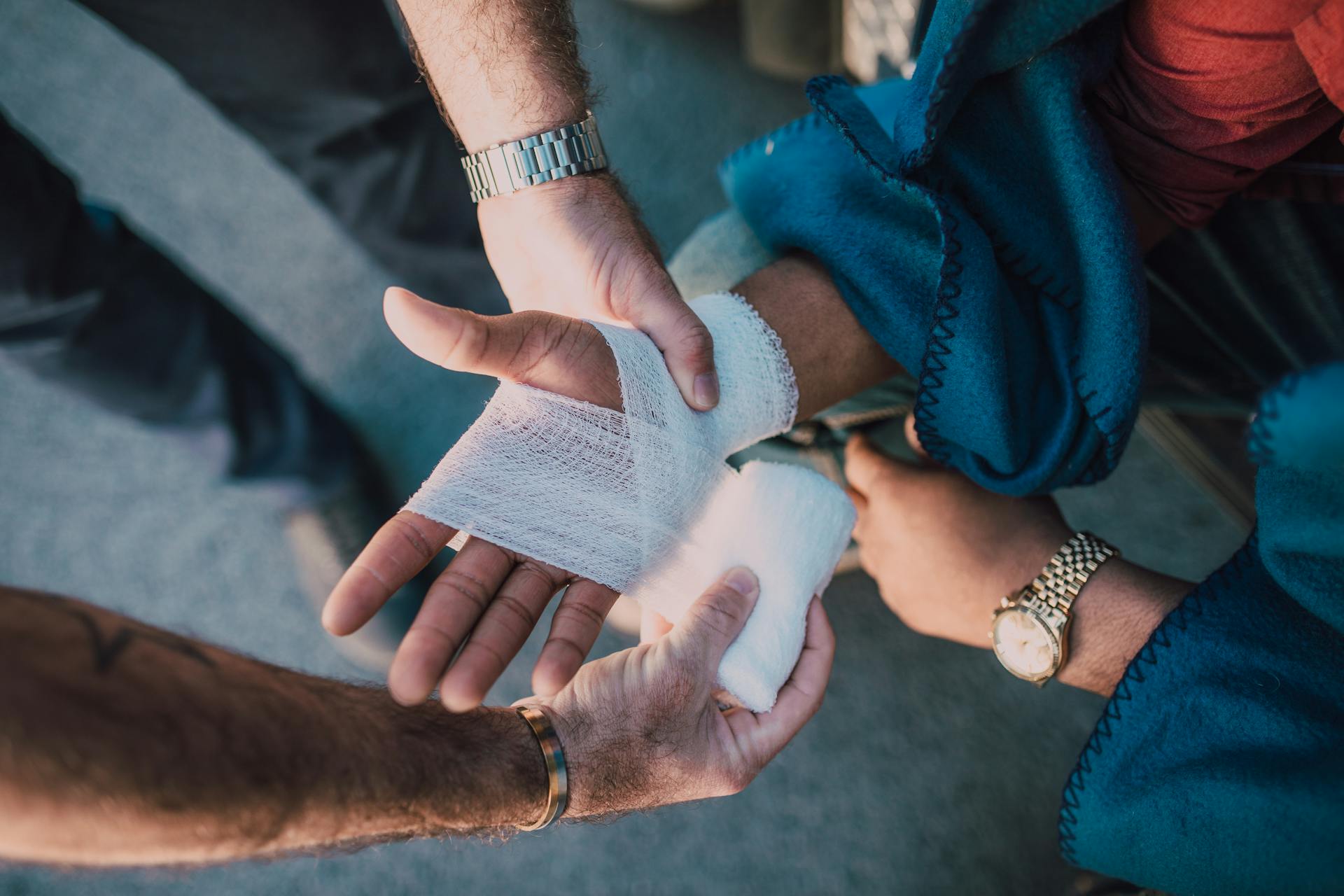 Someone applying bandage to a person's injured hand.