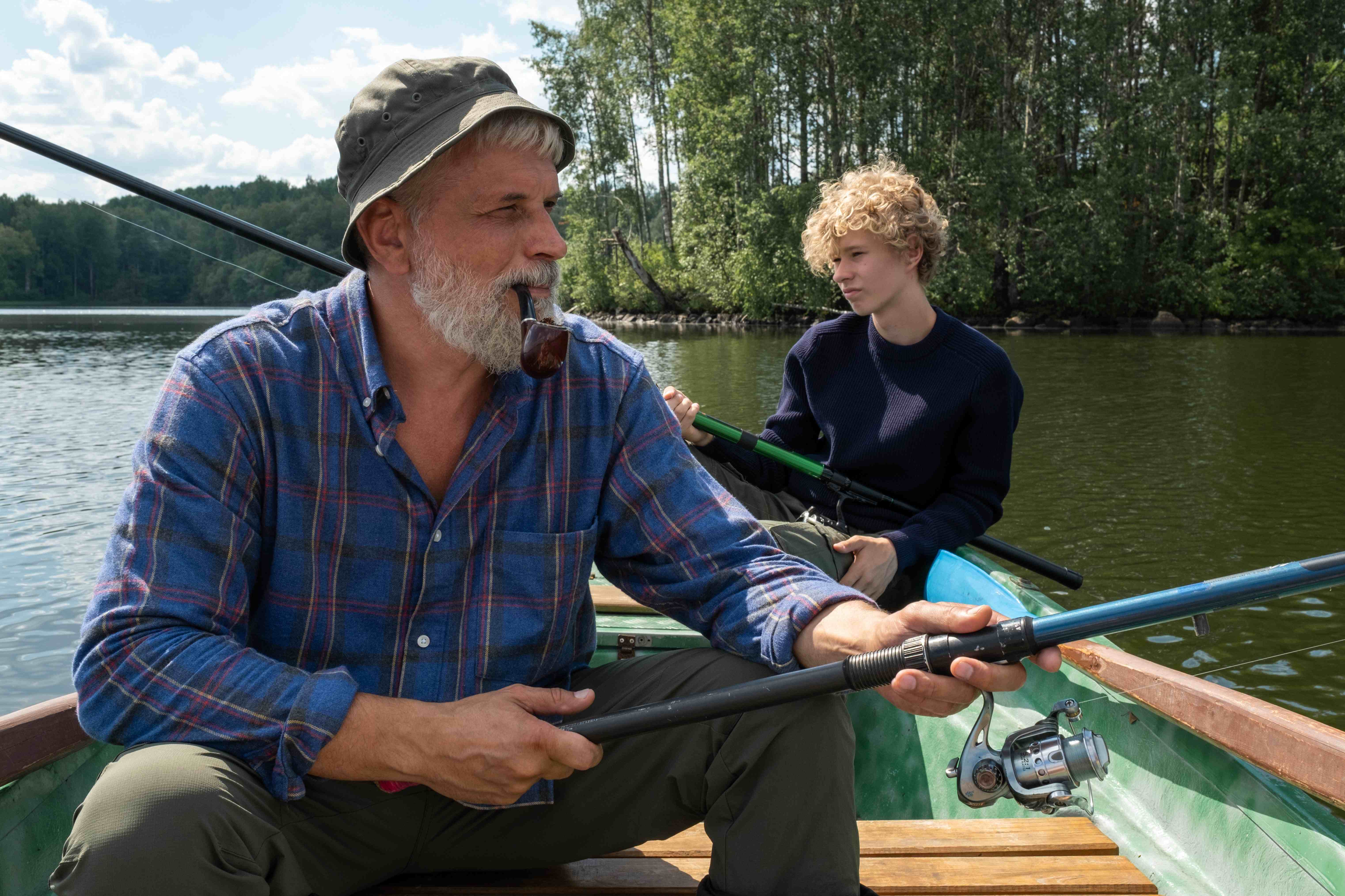 A man and his son fishing in a lake on a sunny day.