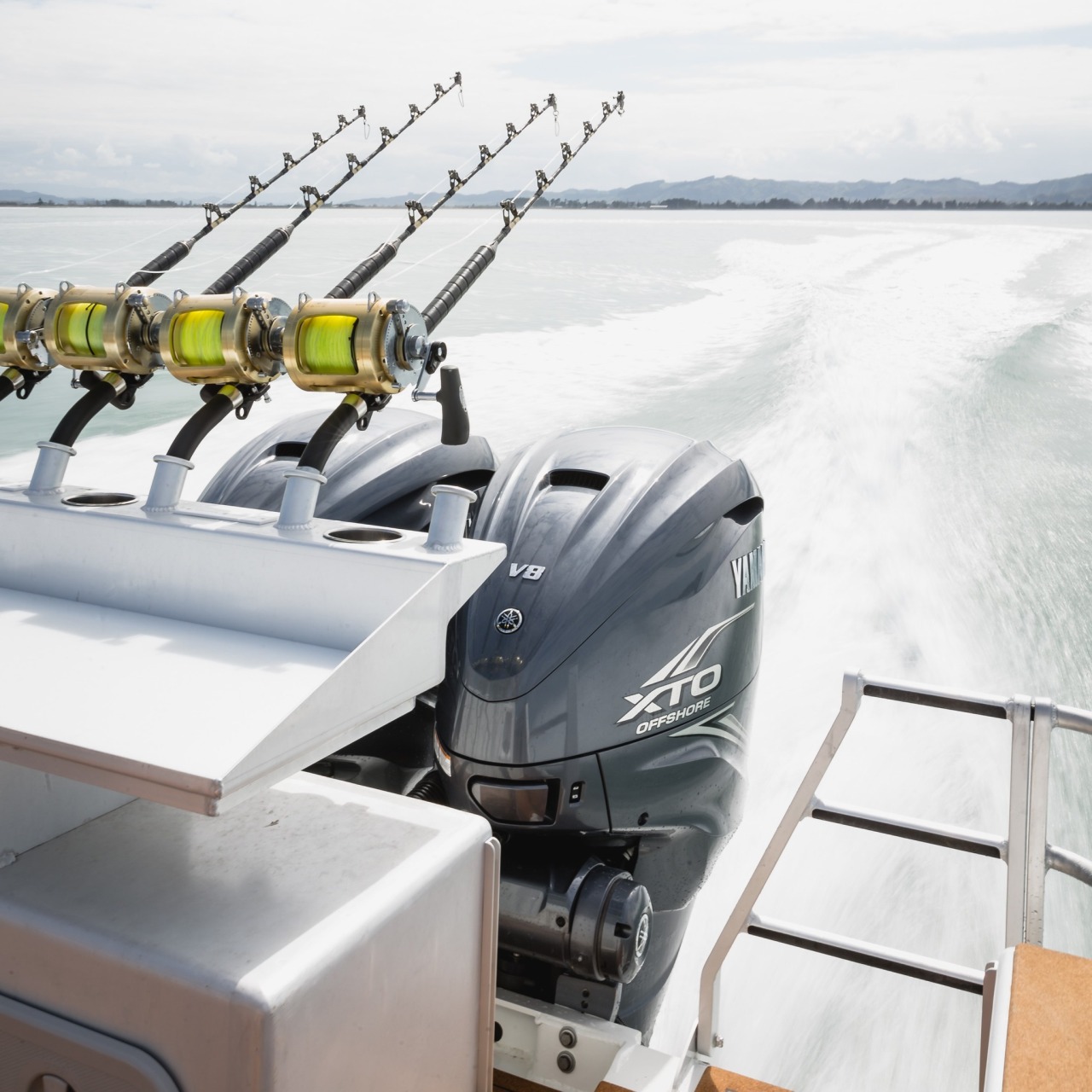 a row of fishing rods and an outboard motor engine installed behind a boat.