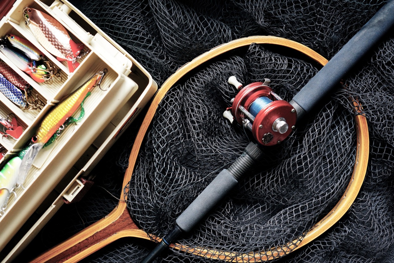 Fishing rod, a fishing net, and a box of fishing lures placed neatly next to each other