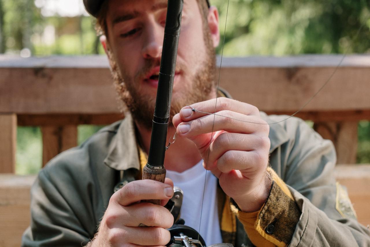 An angler adjusting the fishing line in his rod.