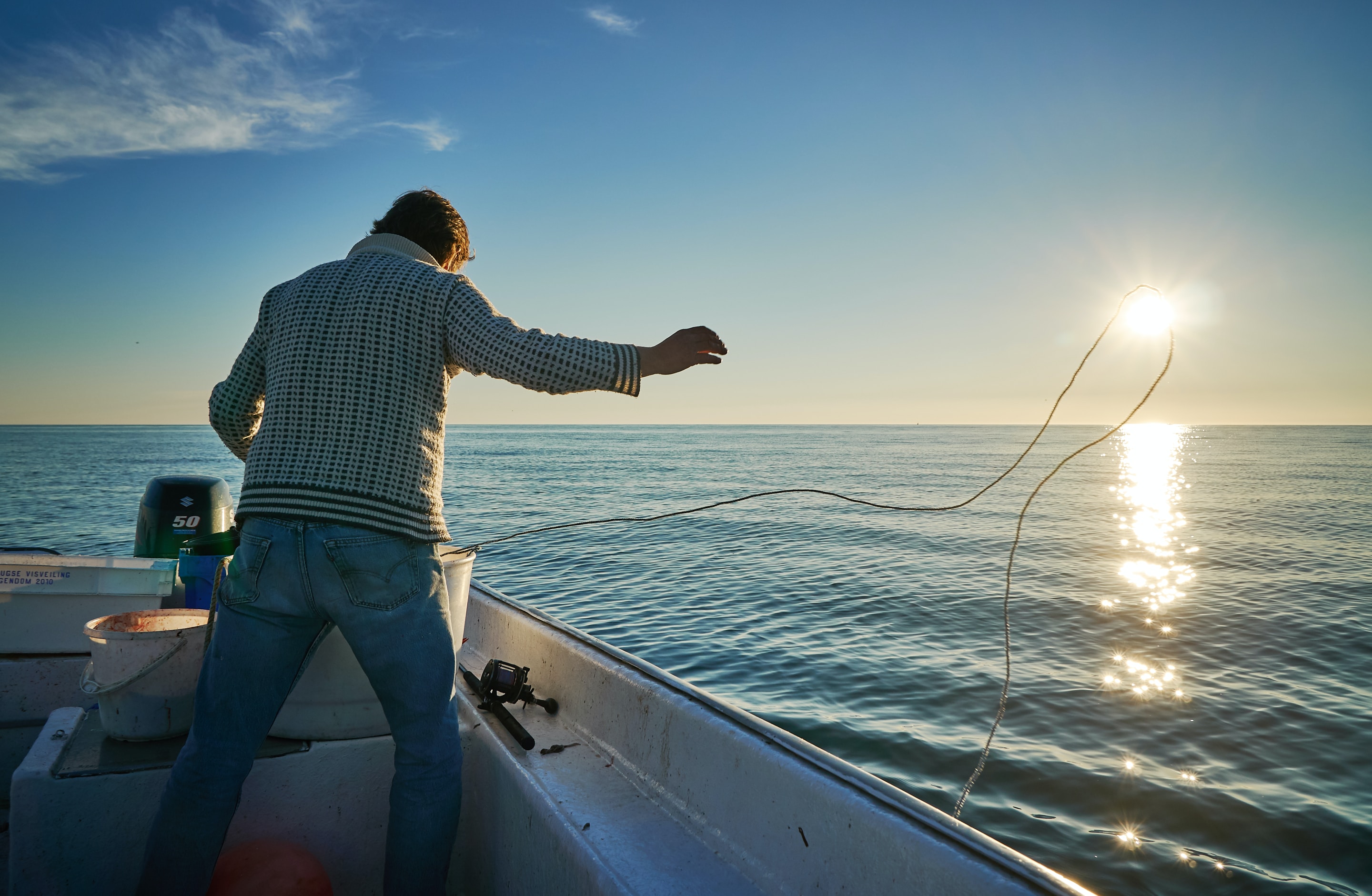 A man casting a line to the water on a fishing boat