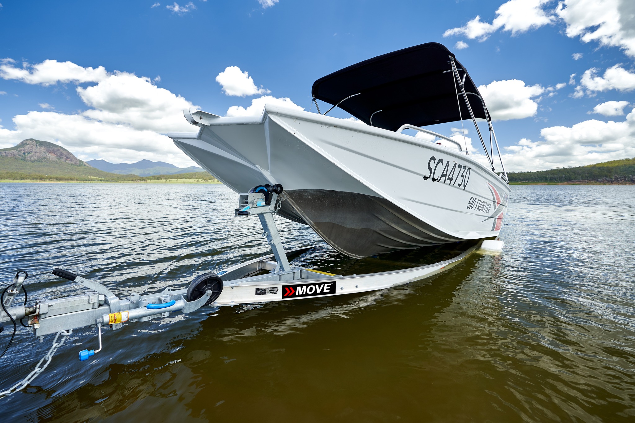 A close up of a boat being launched into the water by a boat trailer.