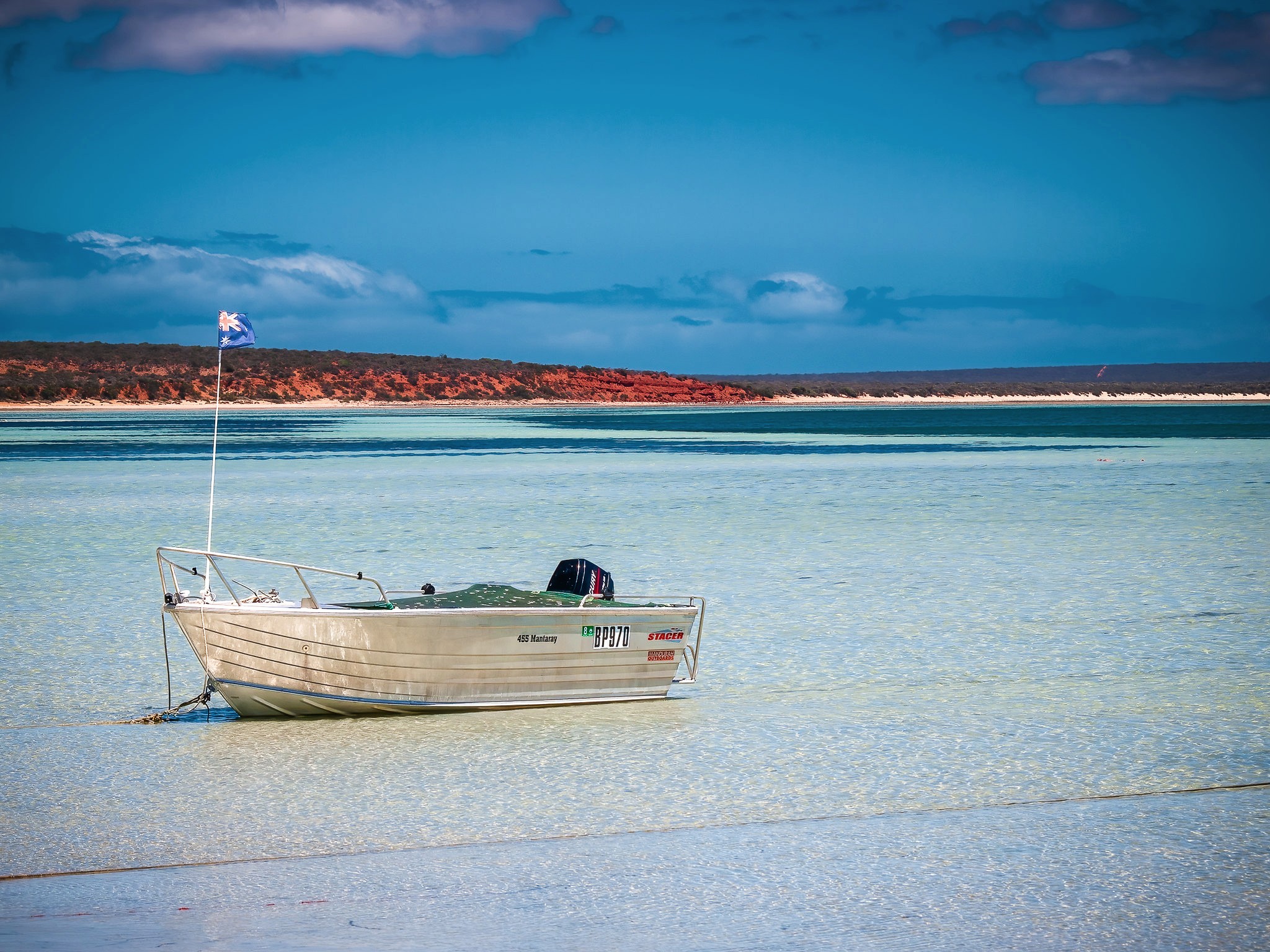 A Stacer tinny is beached on the shore.