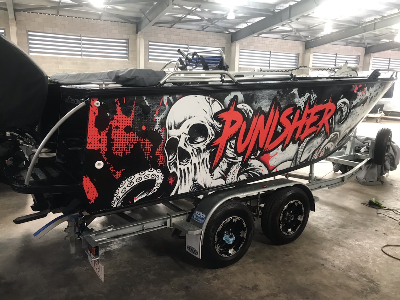 A boat with a cool looking wrap in a boatyard.