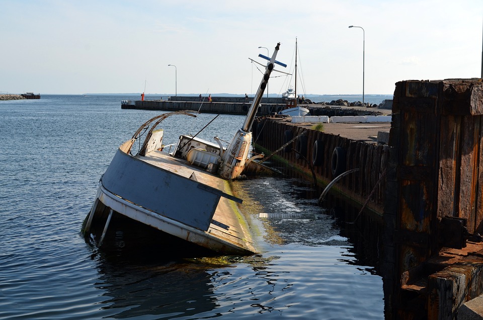 A capsized boat moored next to a dock.