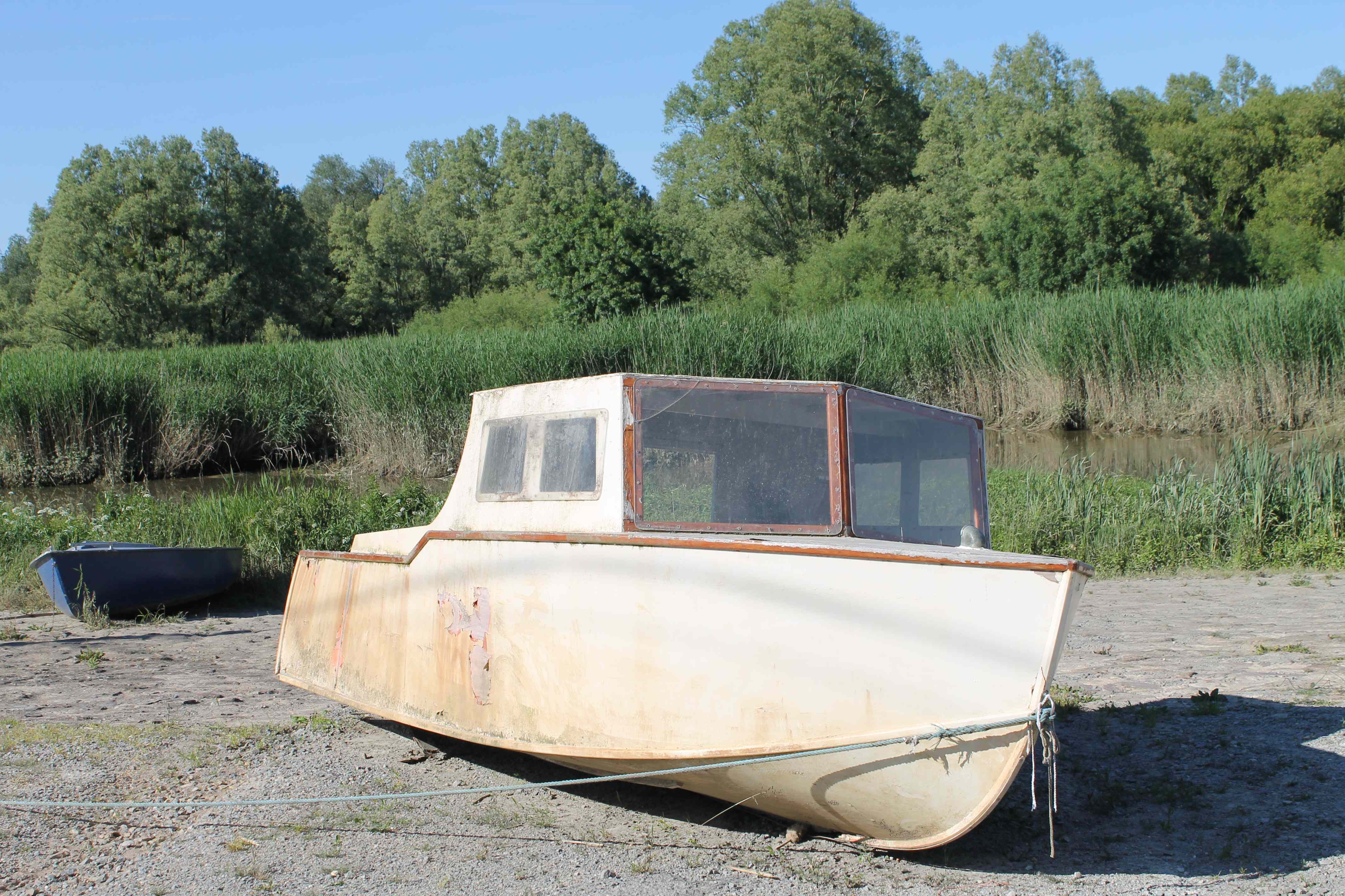 An old and discoloured boat that is grounded on land.