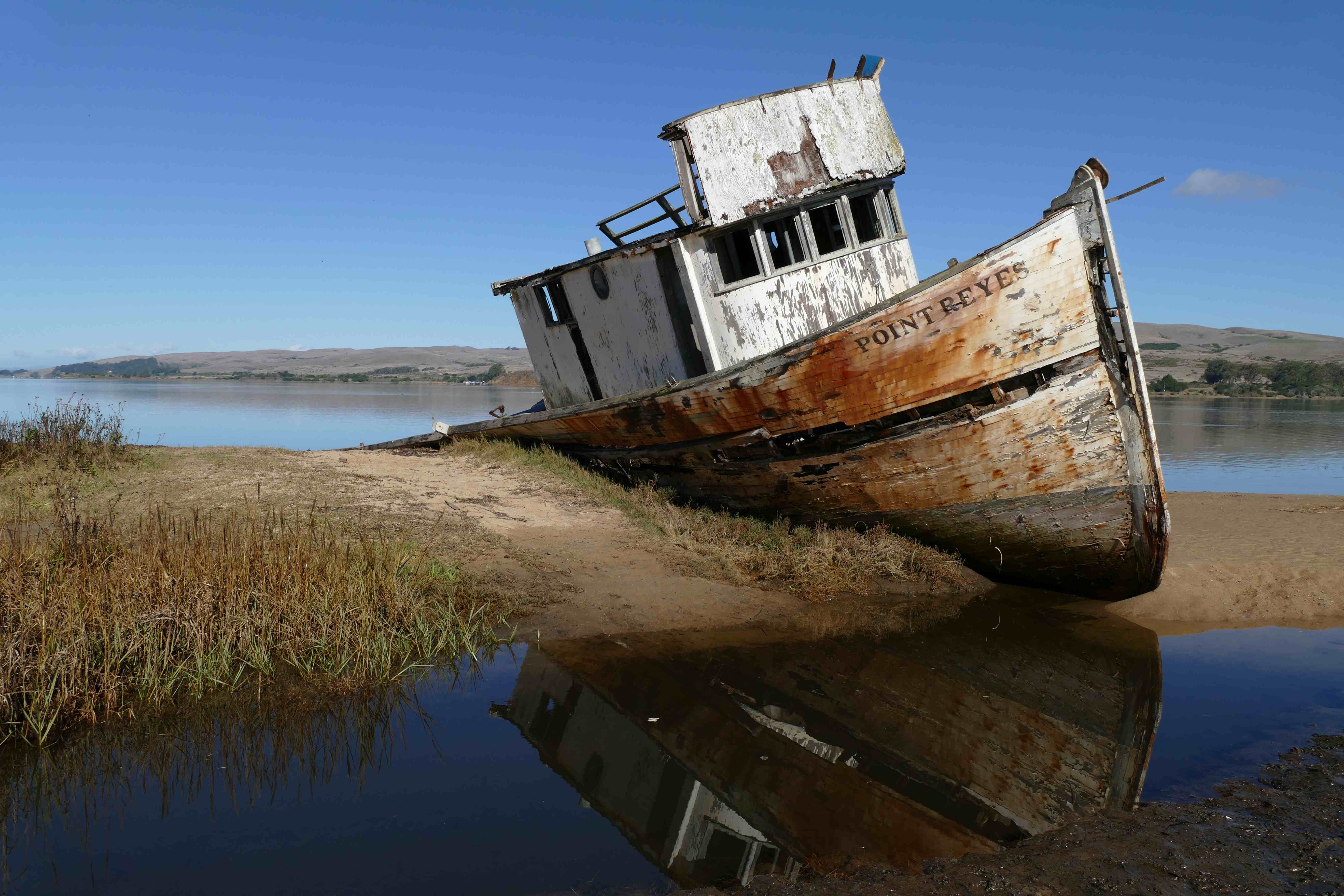 An old ramshackle wooden boat beached at a shore.