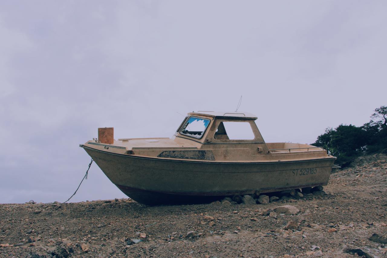 A ramshackle boat sitting on the shore.