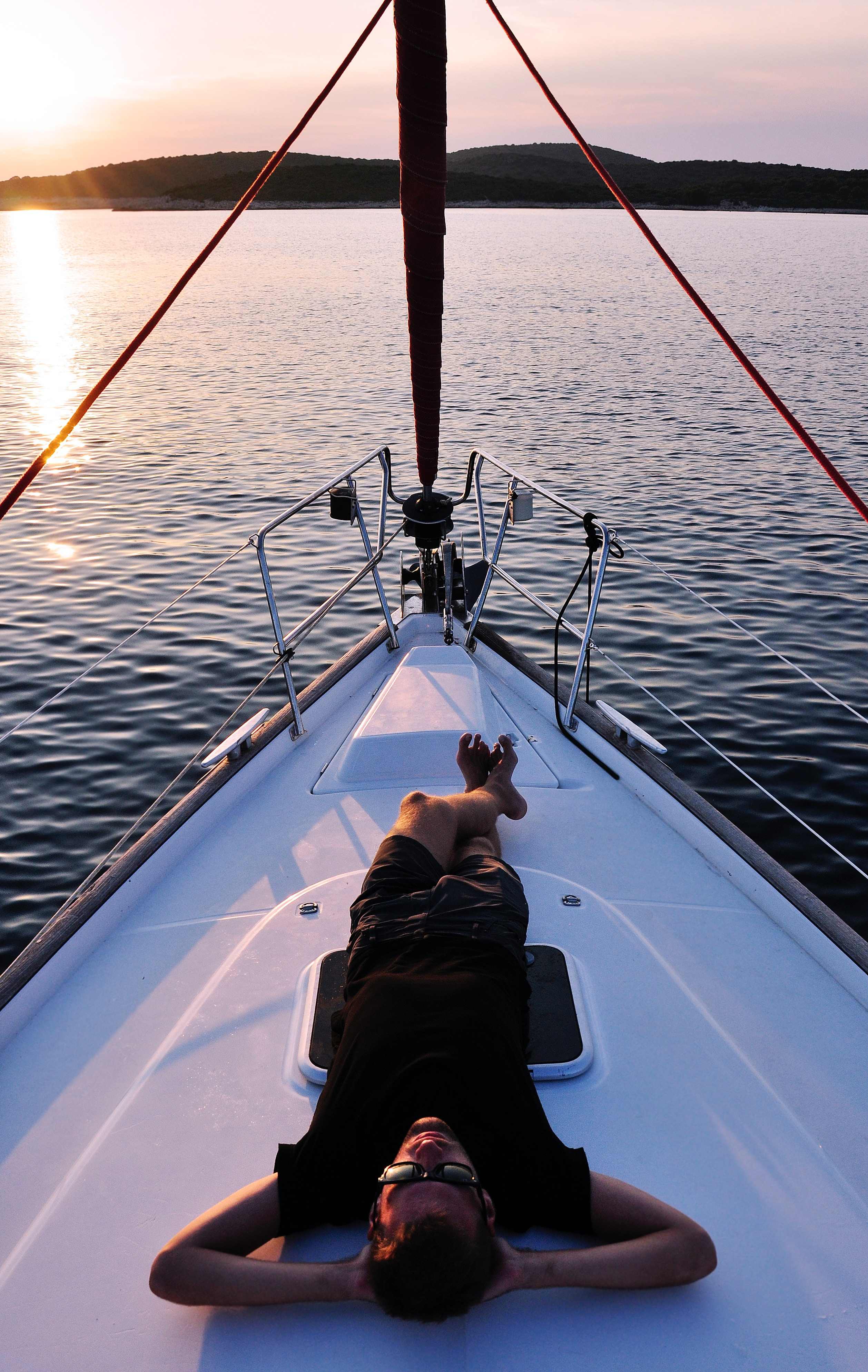 A man lying down on a boat's deck on a sunny afternoon.