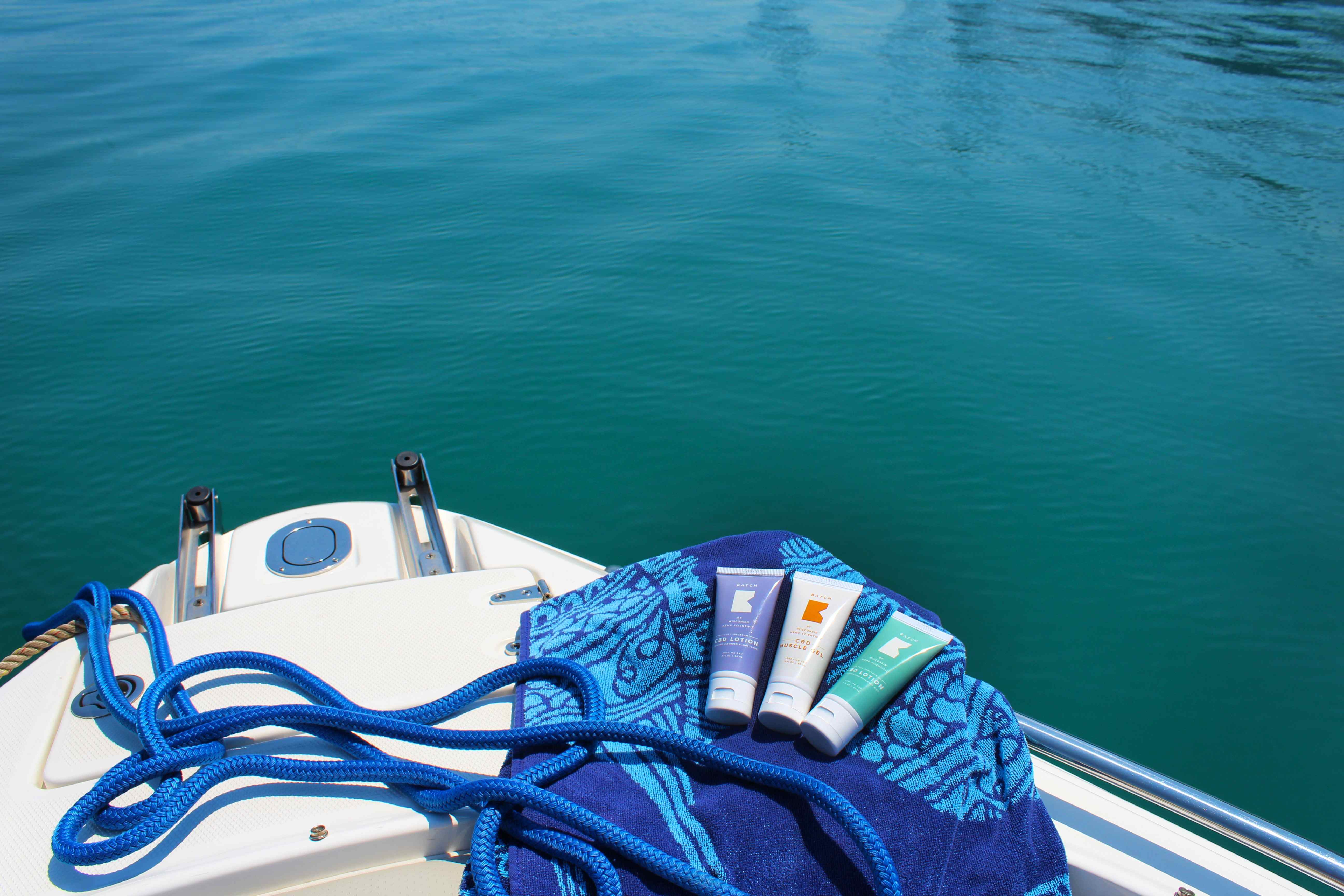 Sunscreen products displayed on a blue towel placed on a white boat's bow