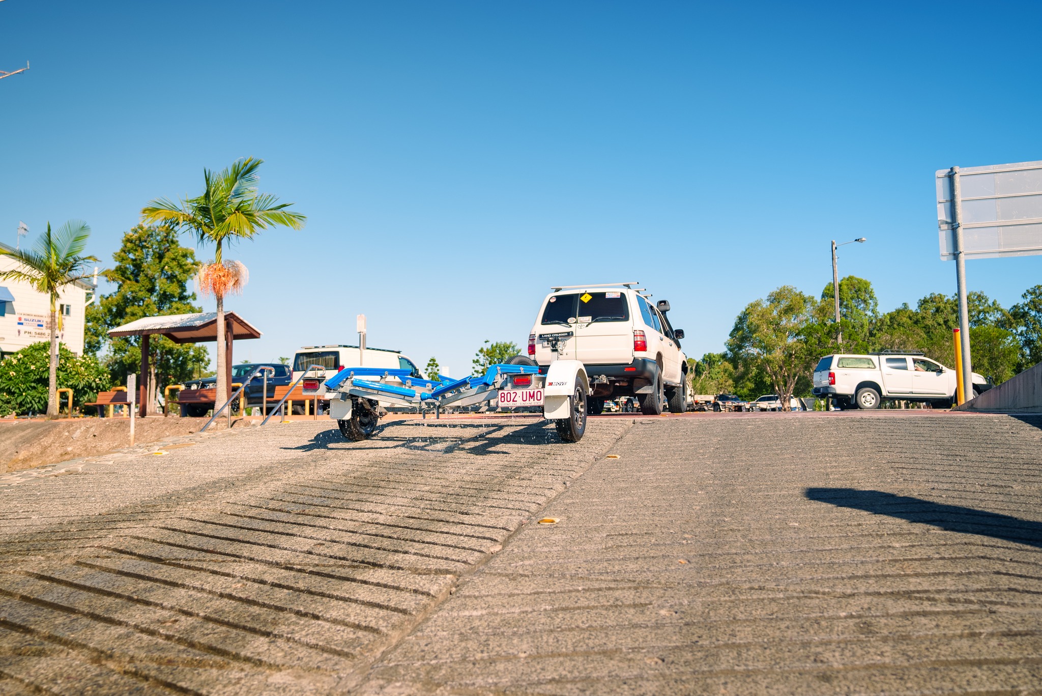 A car with a boat trailer backing down a boat ramp.