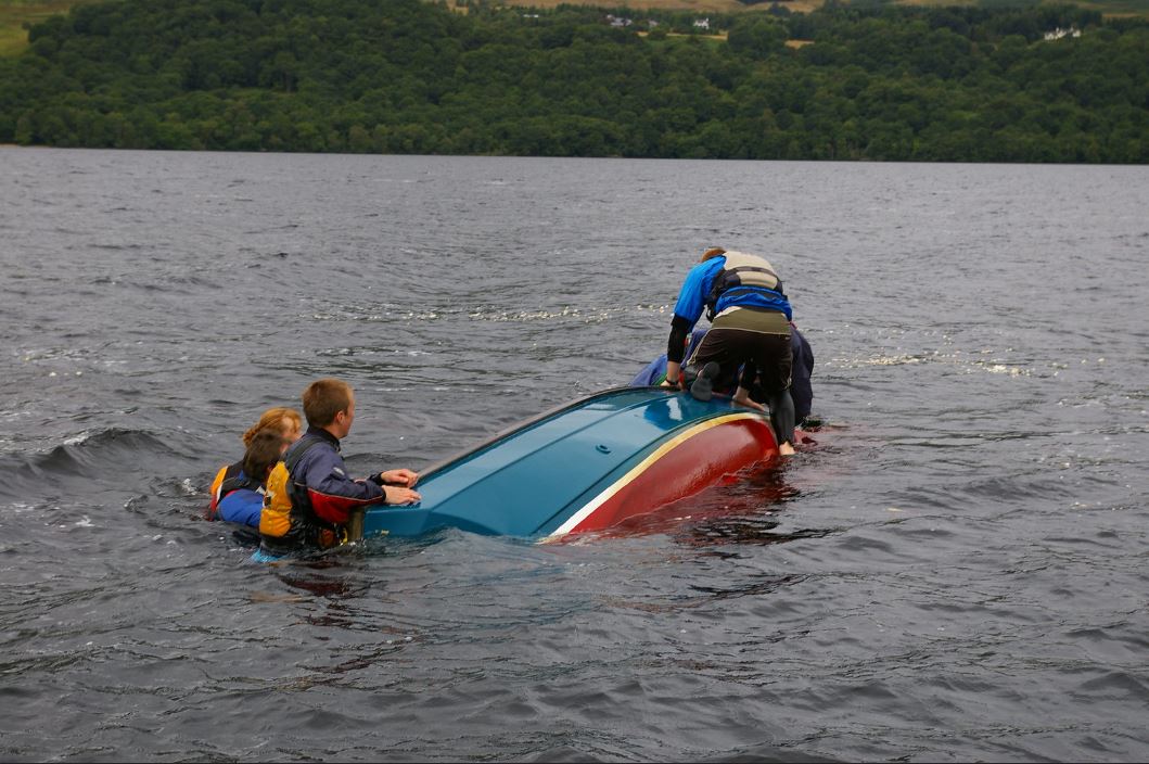 people gathering around the capsized boat.