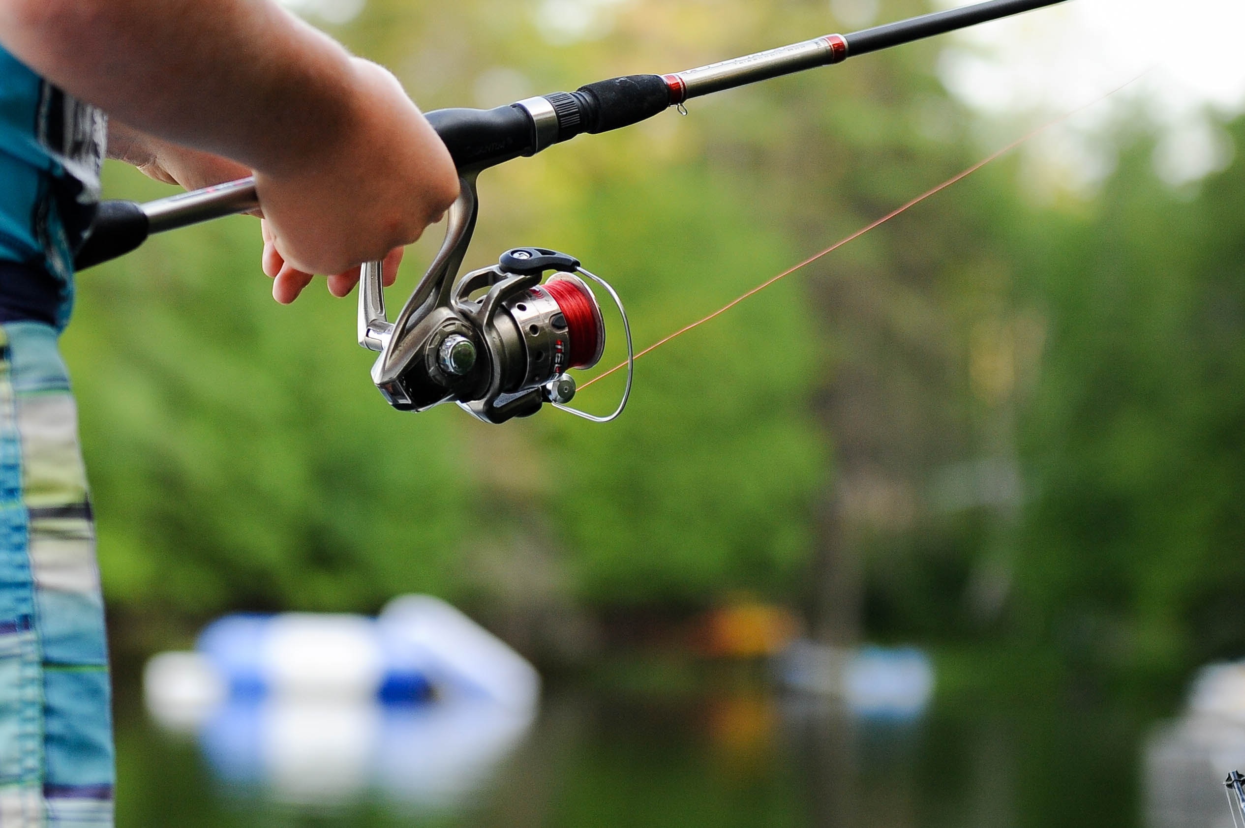 A man holding a fishing rod and reel while fishing on a lake.