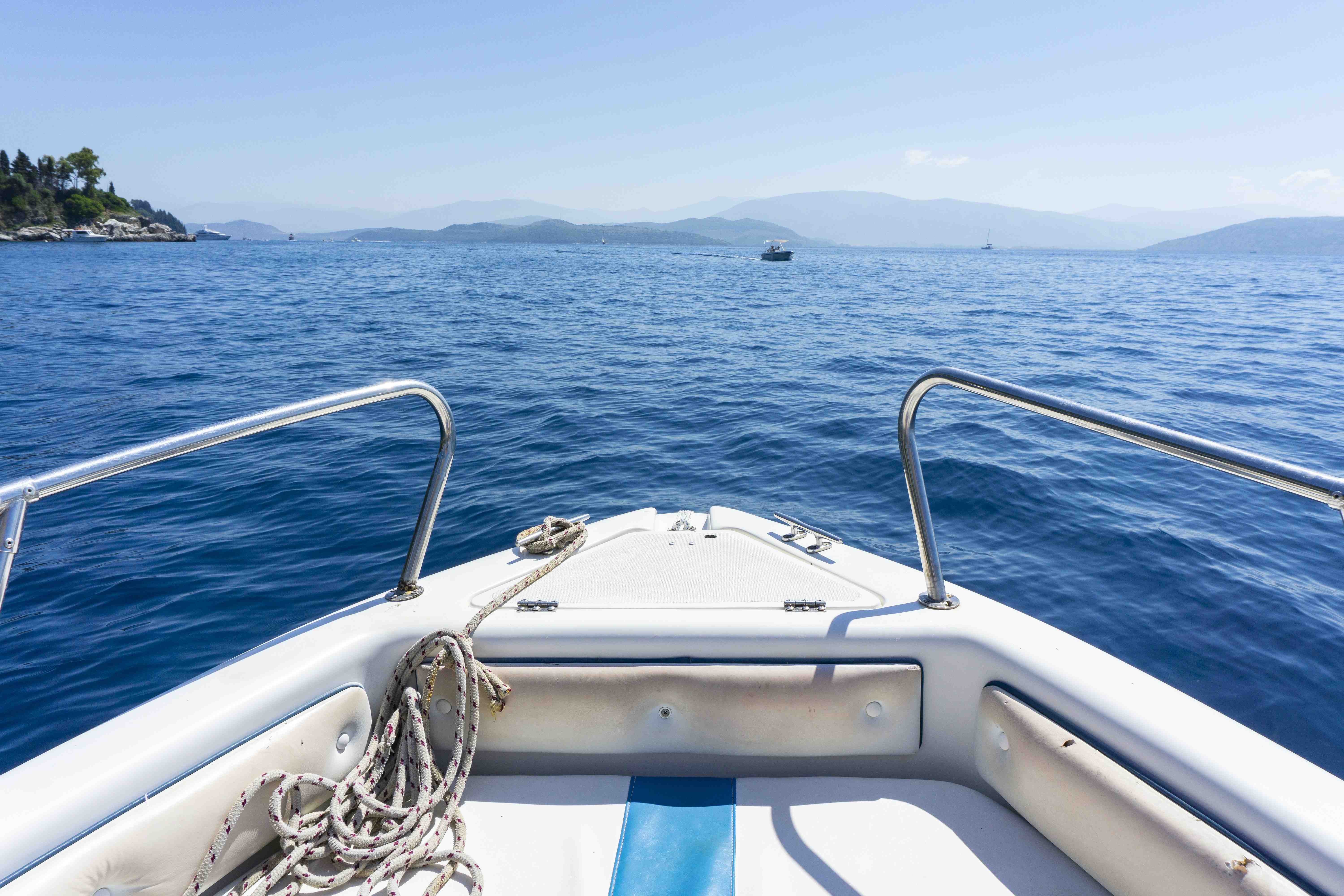 a mid-high angle shot of the front of a white bowrider boat floating on a blue sea.