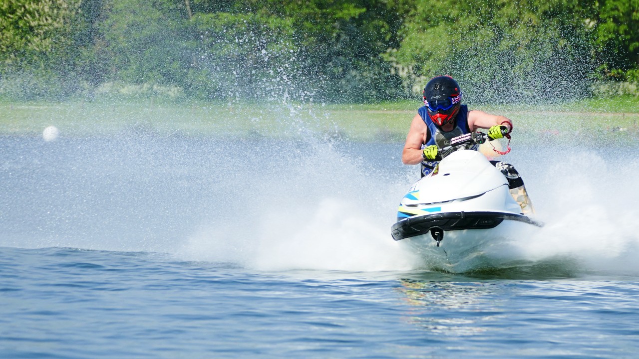 A man wearing a helmet is riding a white jet ski on water.