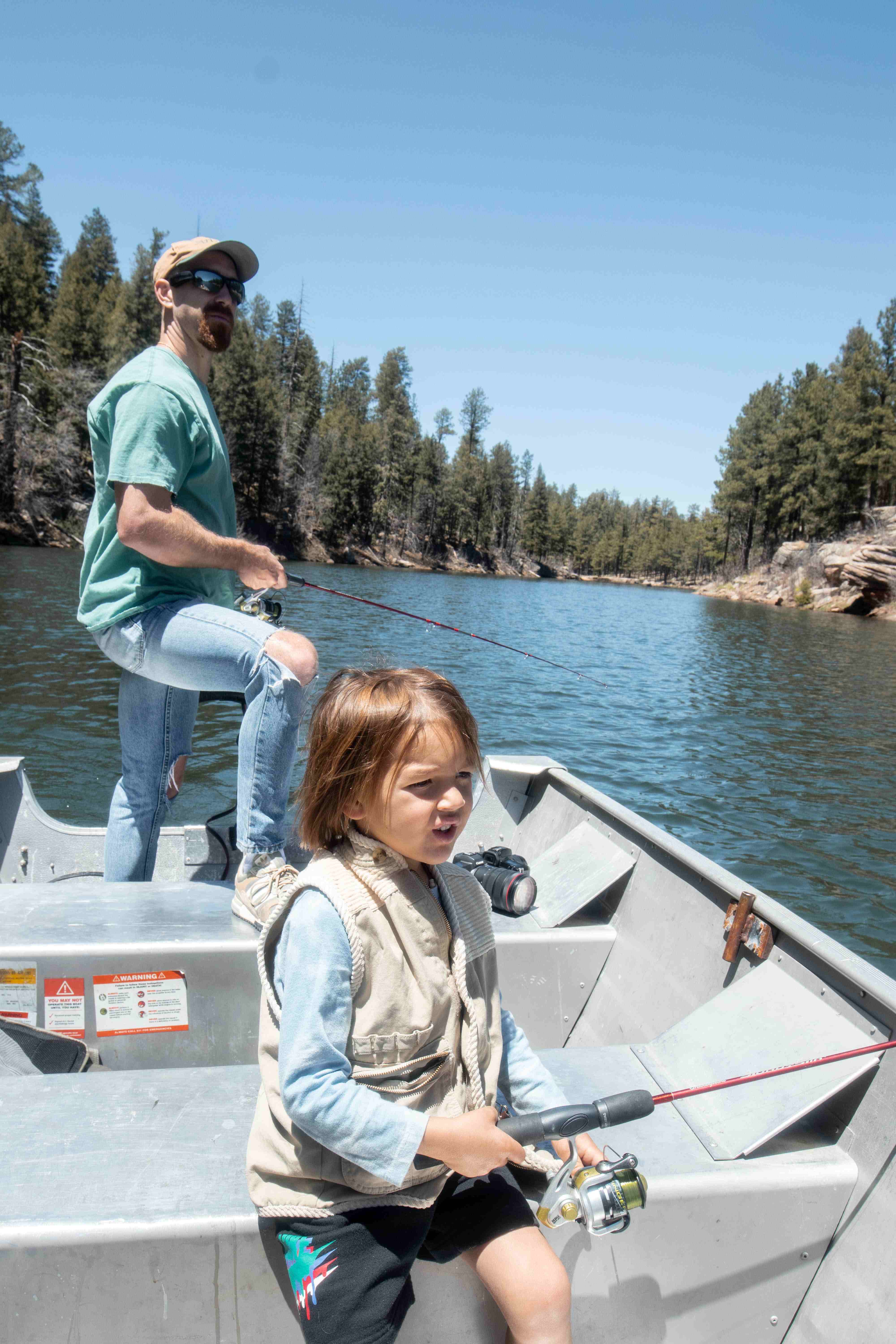 A man and a child fishing on a boat in a river.