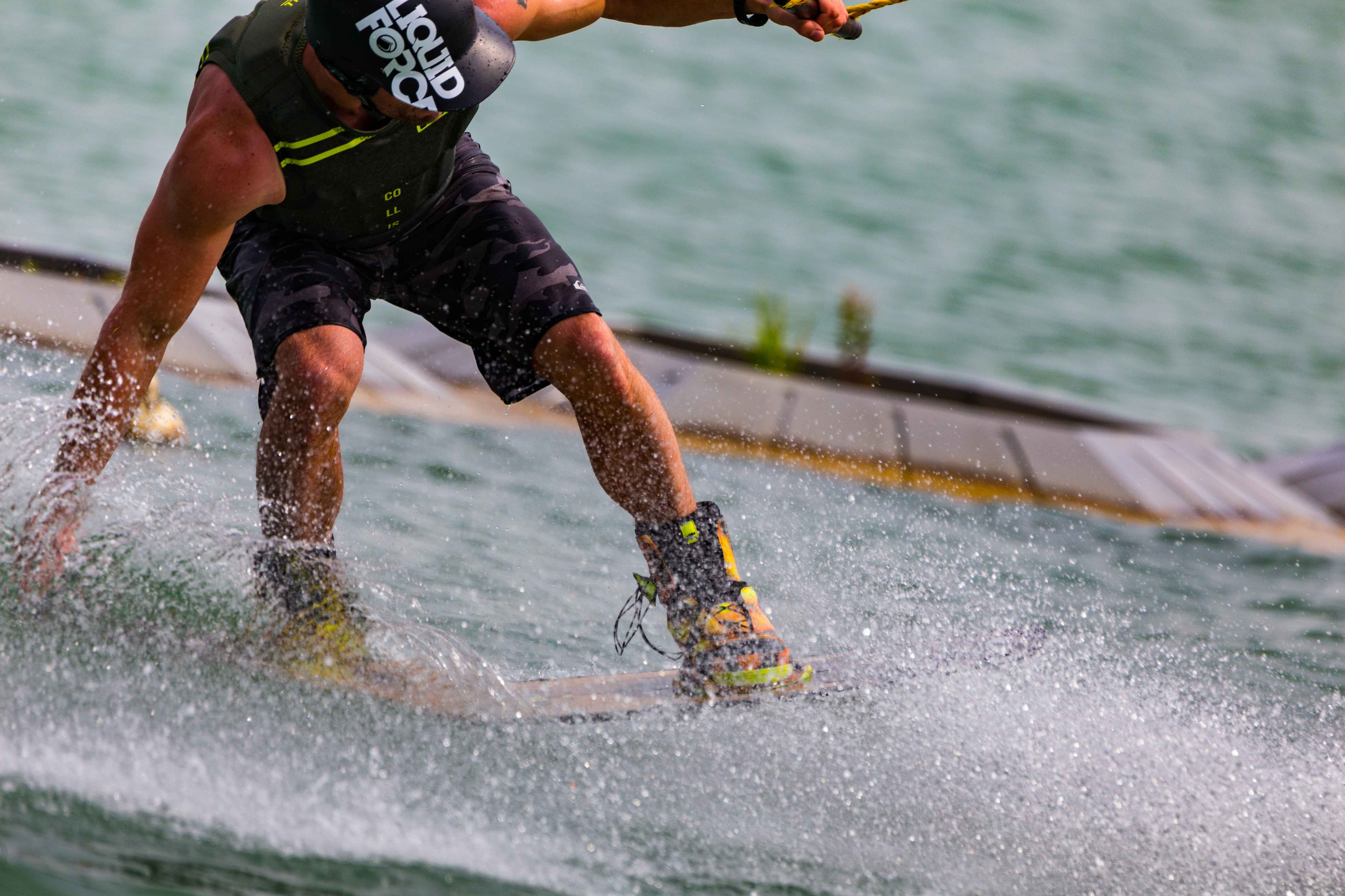 A man running his hand on the water as he is wakeboarding.