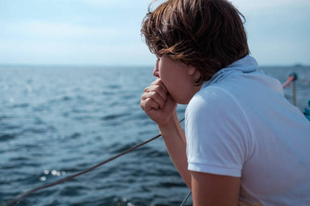 A man experiencing sickness while on a boat out at sea.