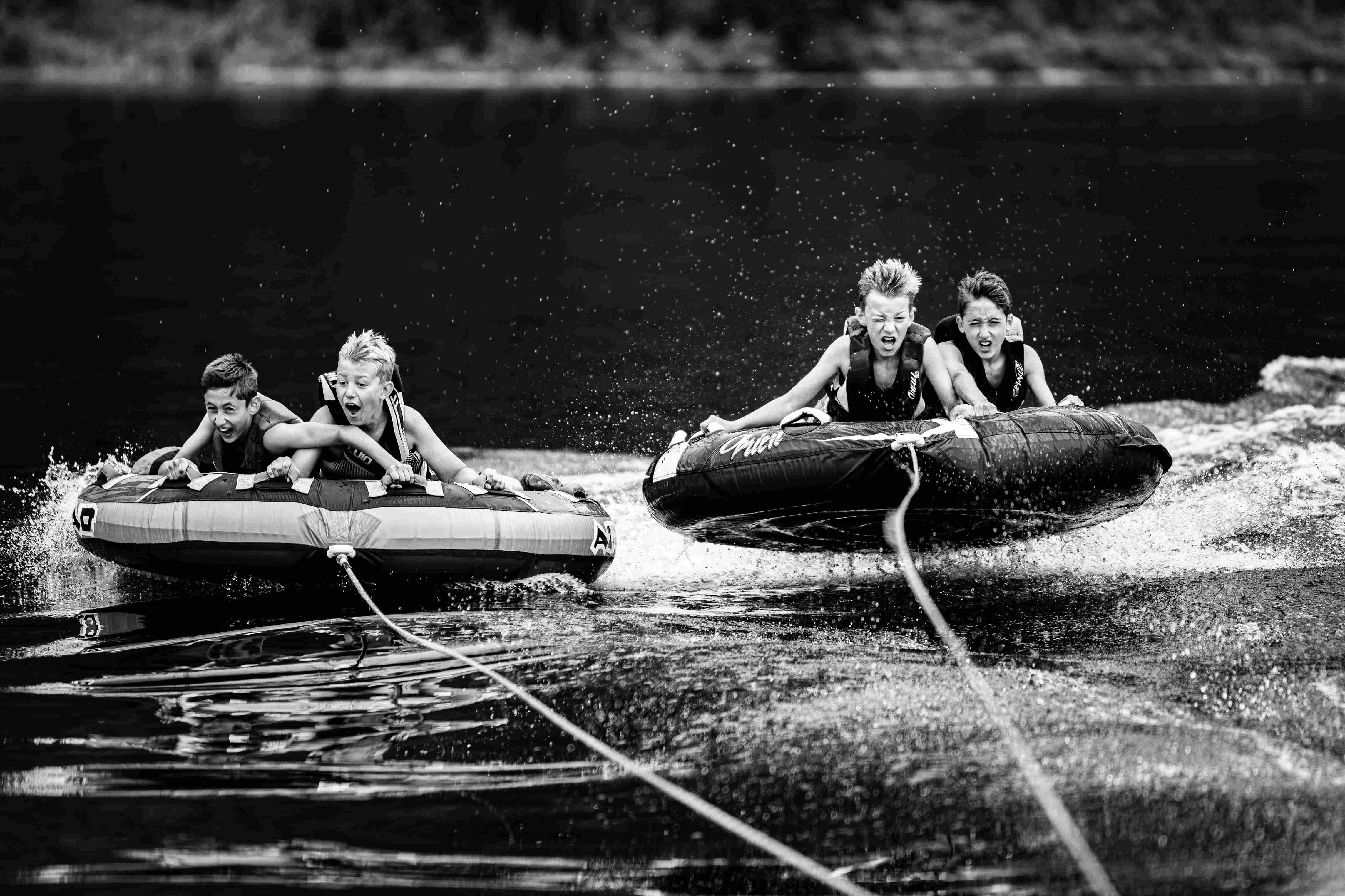 a black and white photo of young boys riding a tow tube.