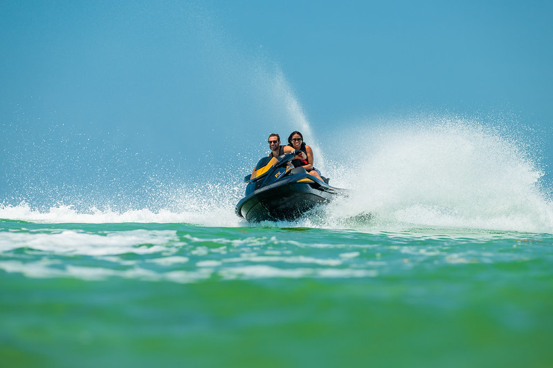 A man wearing a helmet is riding a white jet ski on water.
