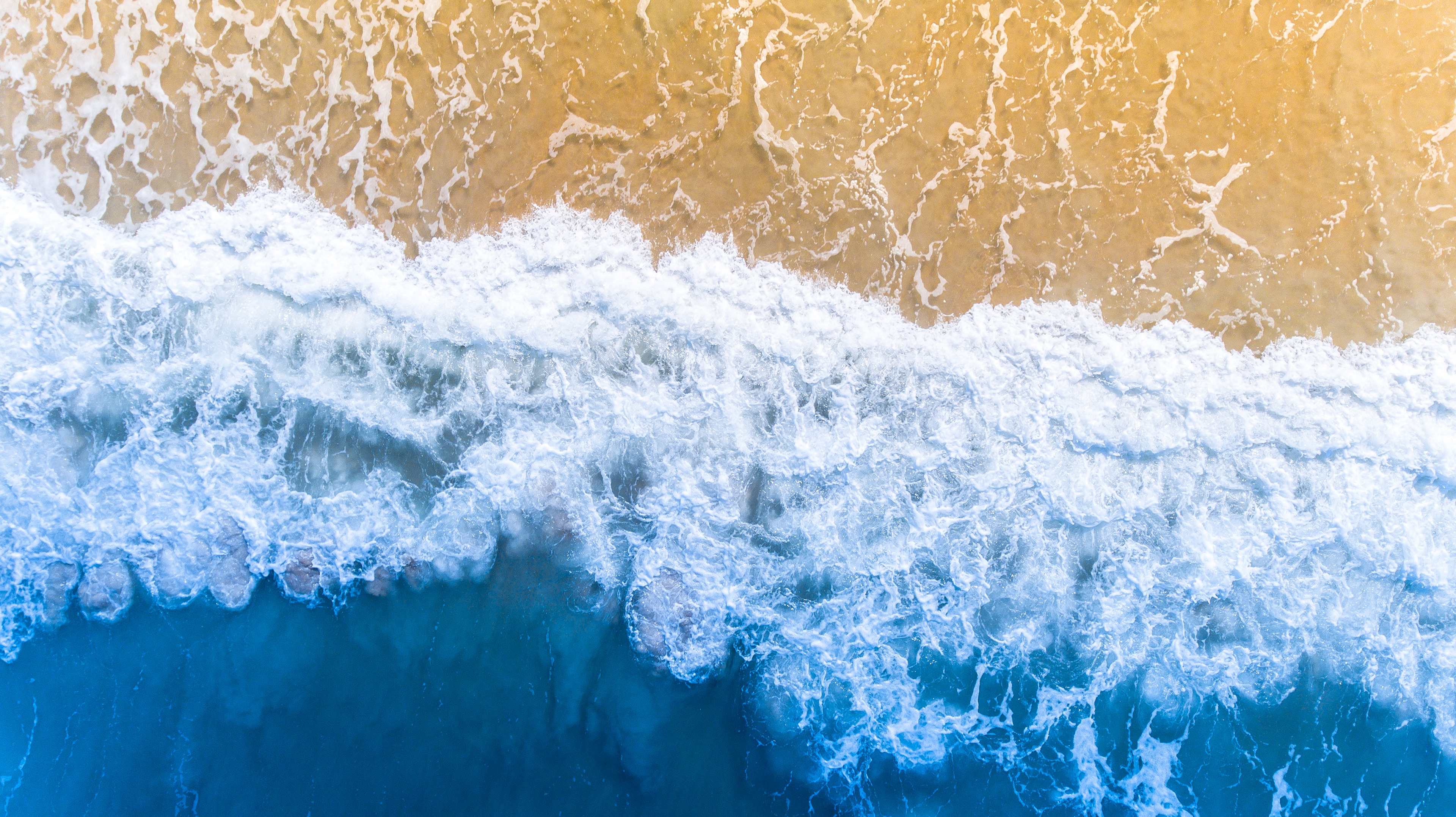 A bird's eye view of the waves on a beach.