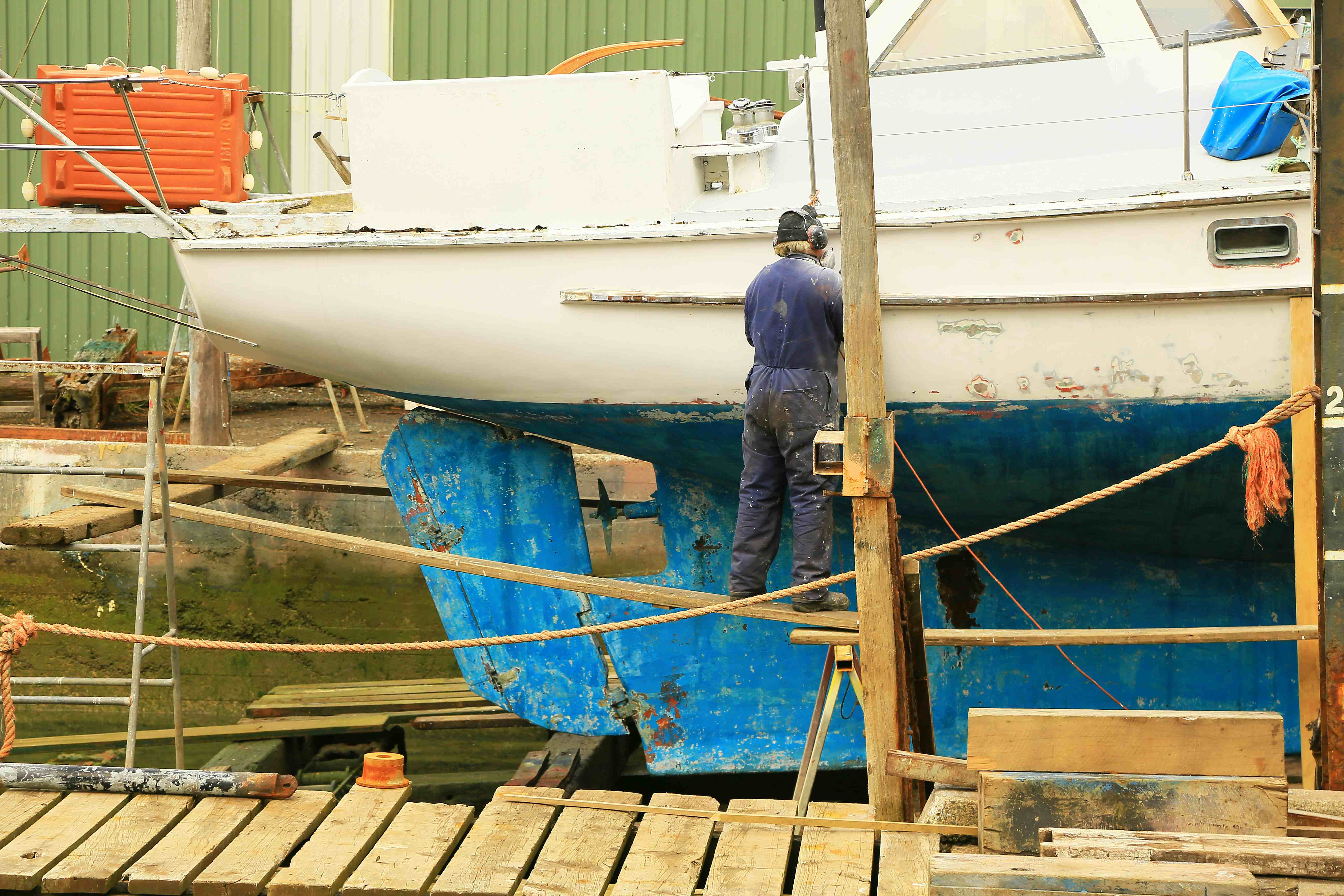 A man repairing a boat in a shipyard.